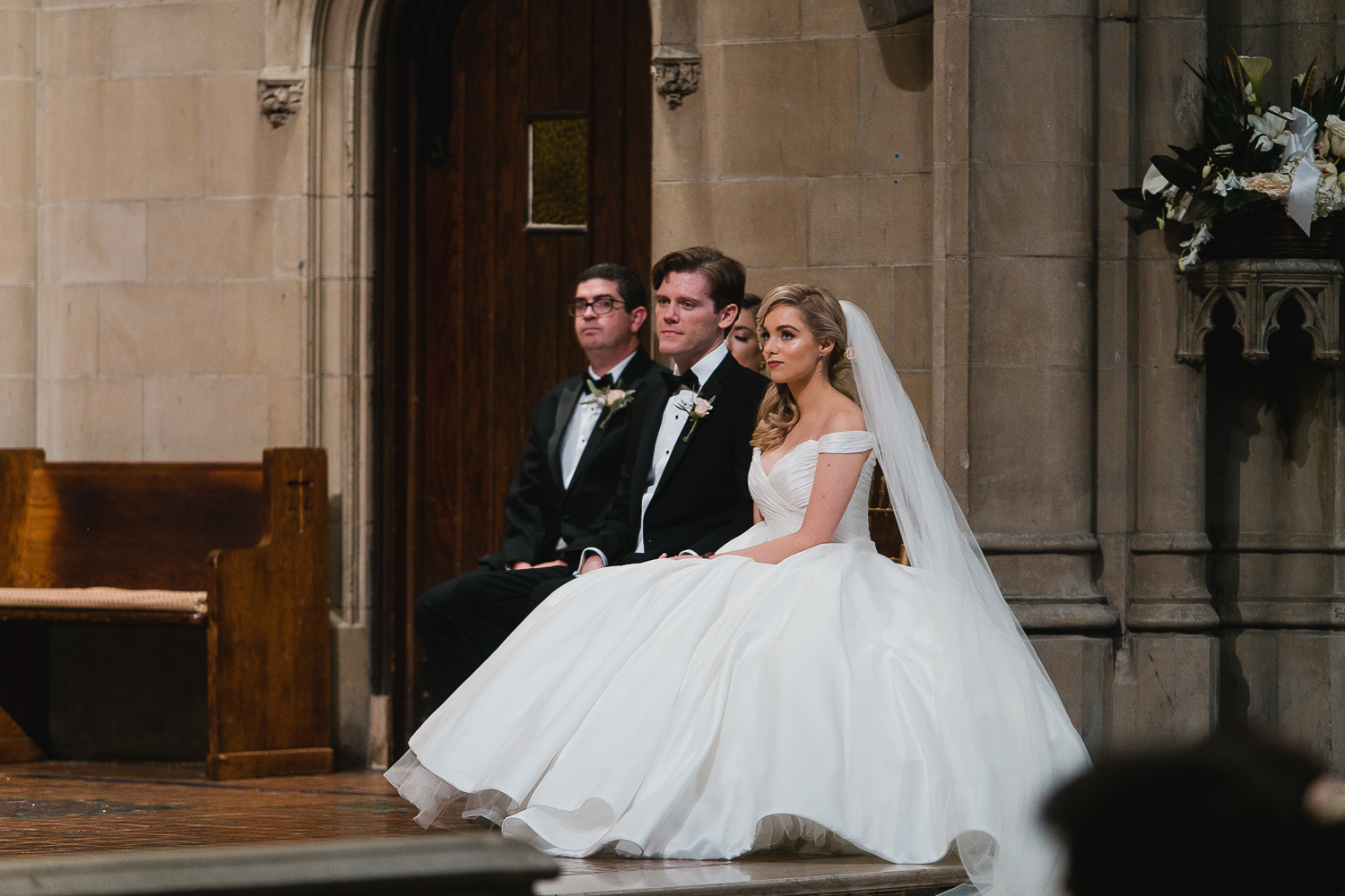 Catholic wedding ceremony, bride and groom are sitting and listening.