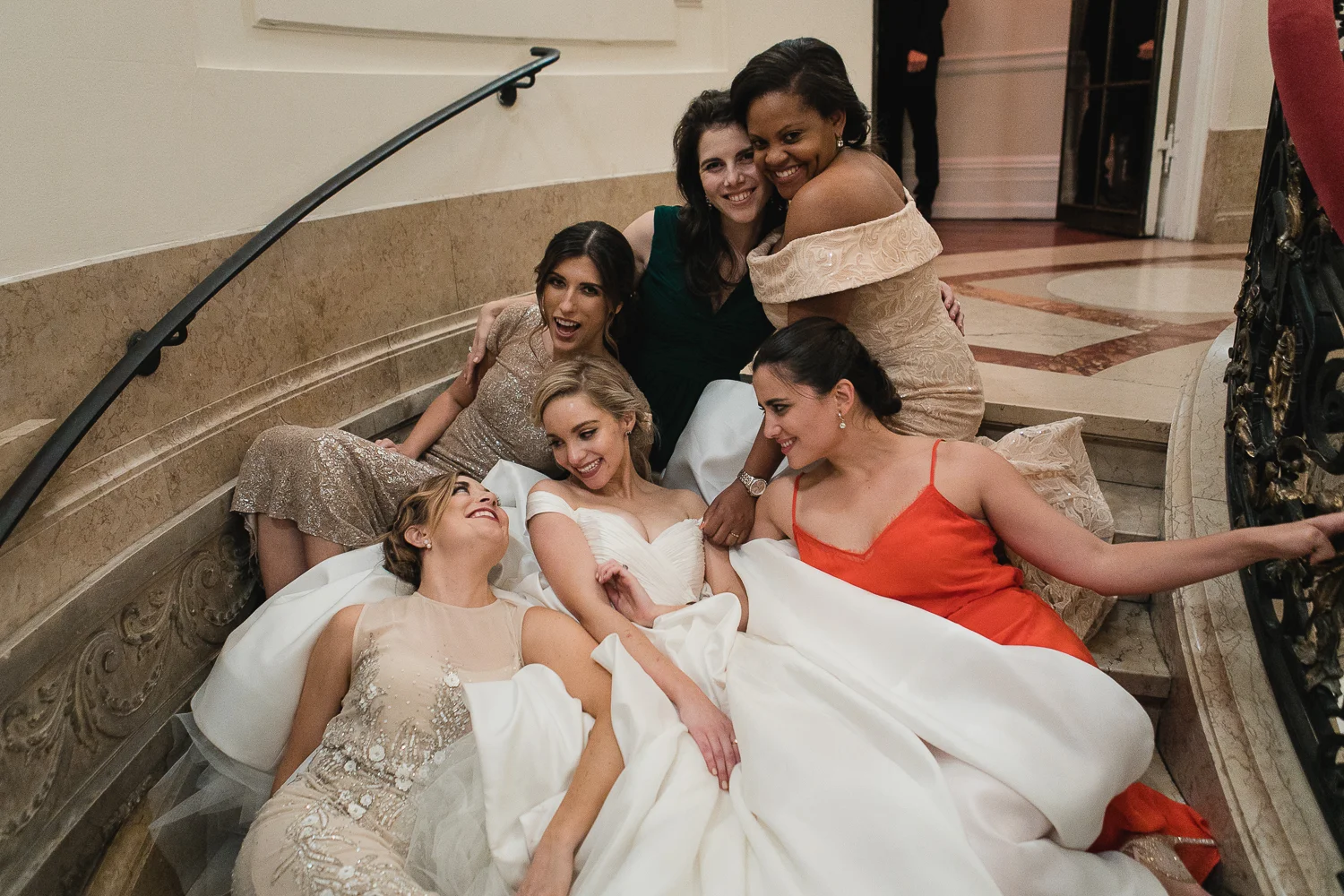 Bride and her bridesmaids hugging on the steps of James Burden Mansion.