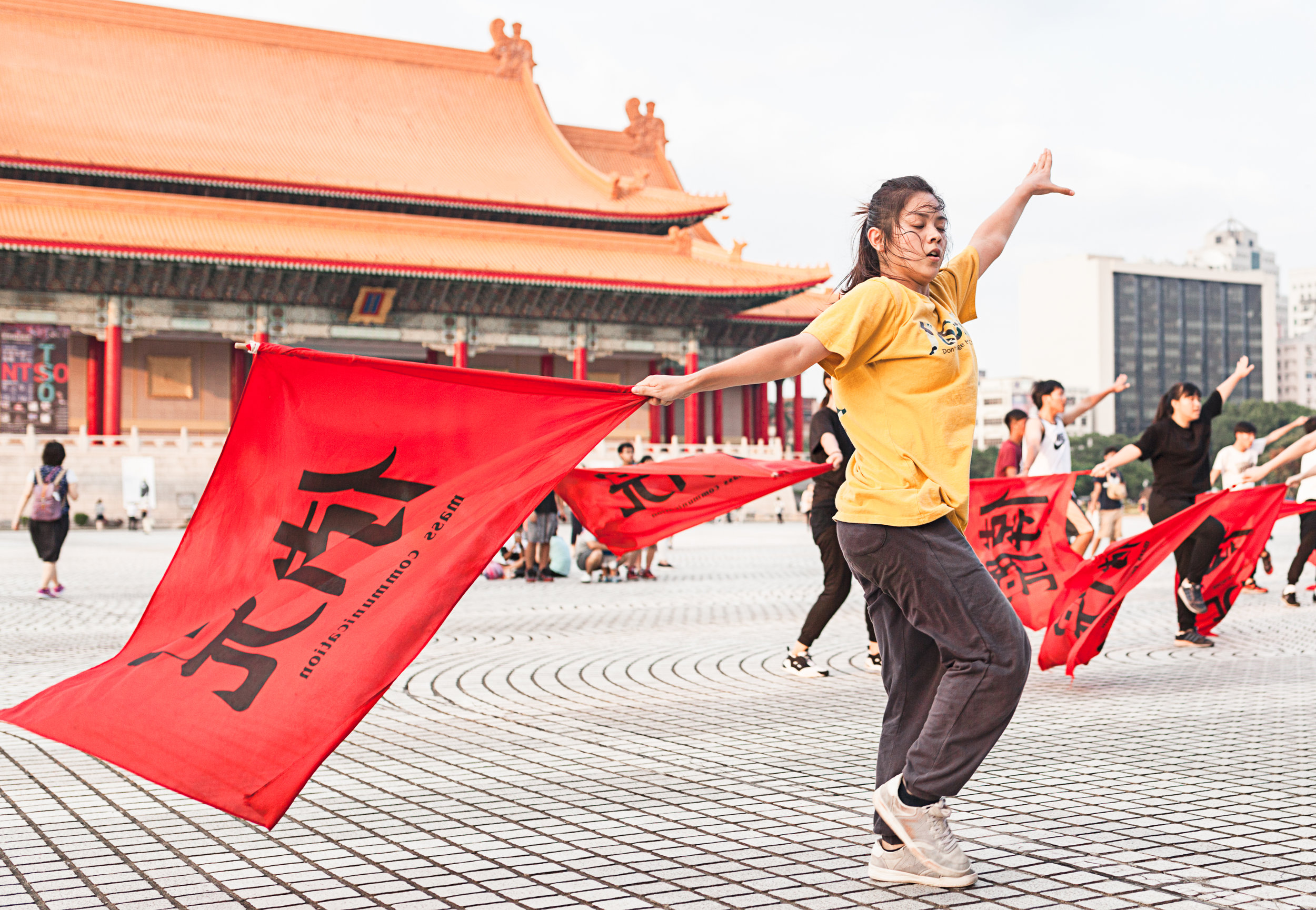 Flag dancer frozen mid-routine against a backdrop of the Taiwan National Concert Hall
