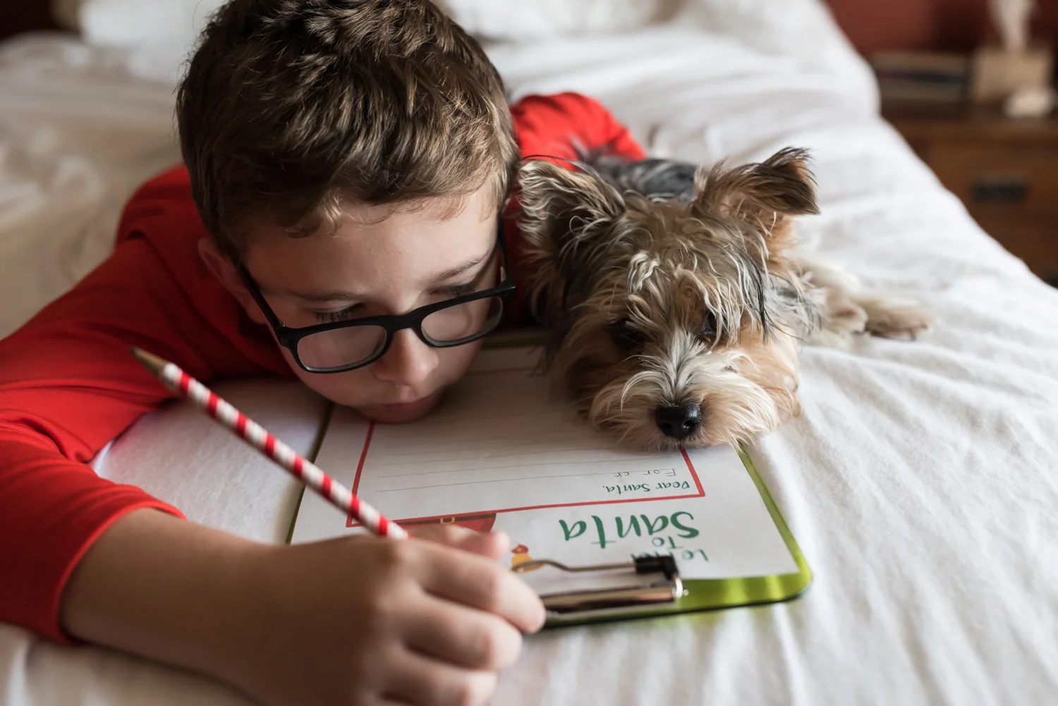 Boy and Puppy writing their Santa Letter on a Bed