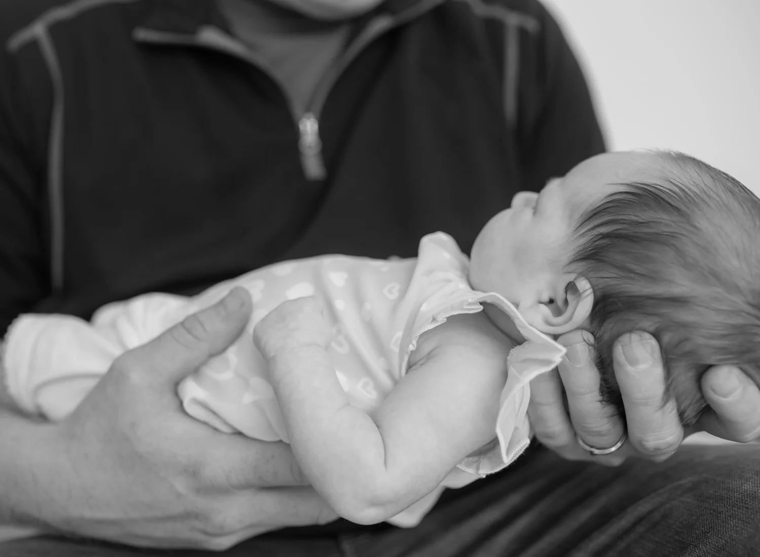 Baby girl being held in her father's hands.