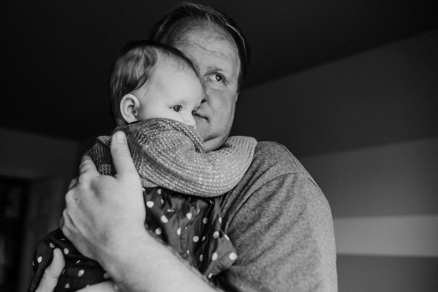 Dad hugging his baby looking out the window.