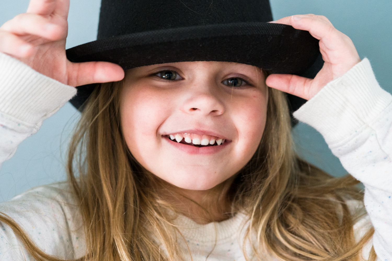 Portrait of a girl wearing a hat and holding the brim during dramactic play at daycare in Fargo.