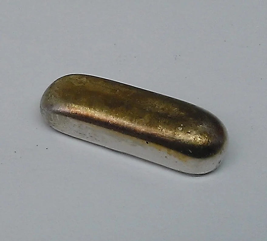 The melted down white gold forming an ingot bar.