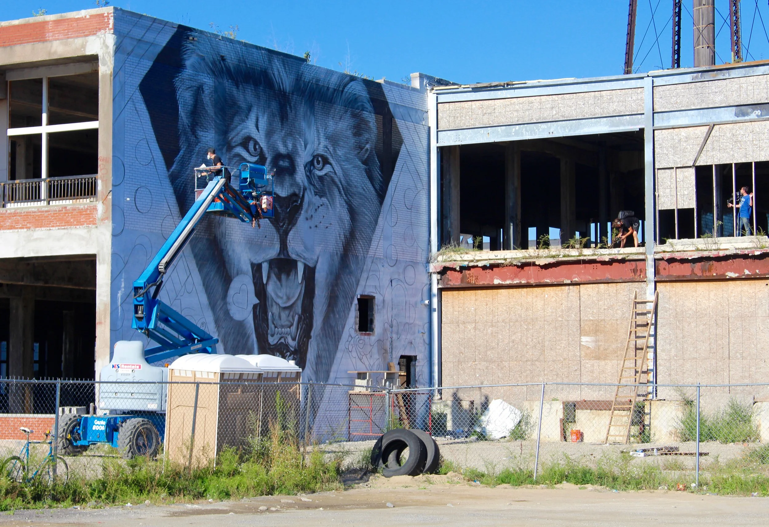 Artist Greg Mike working on his wall, accompanied by an audience 
