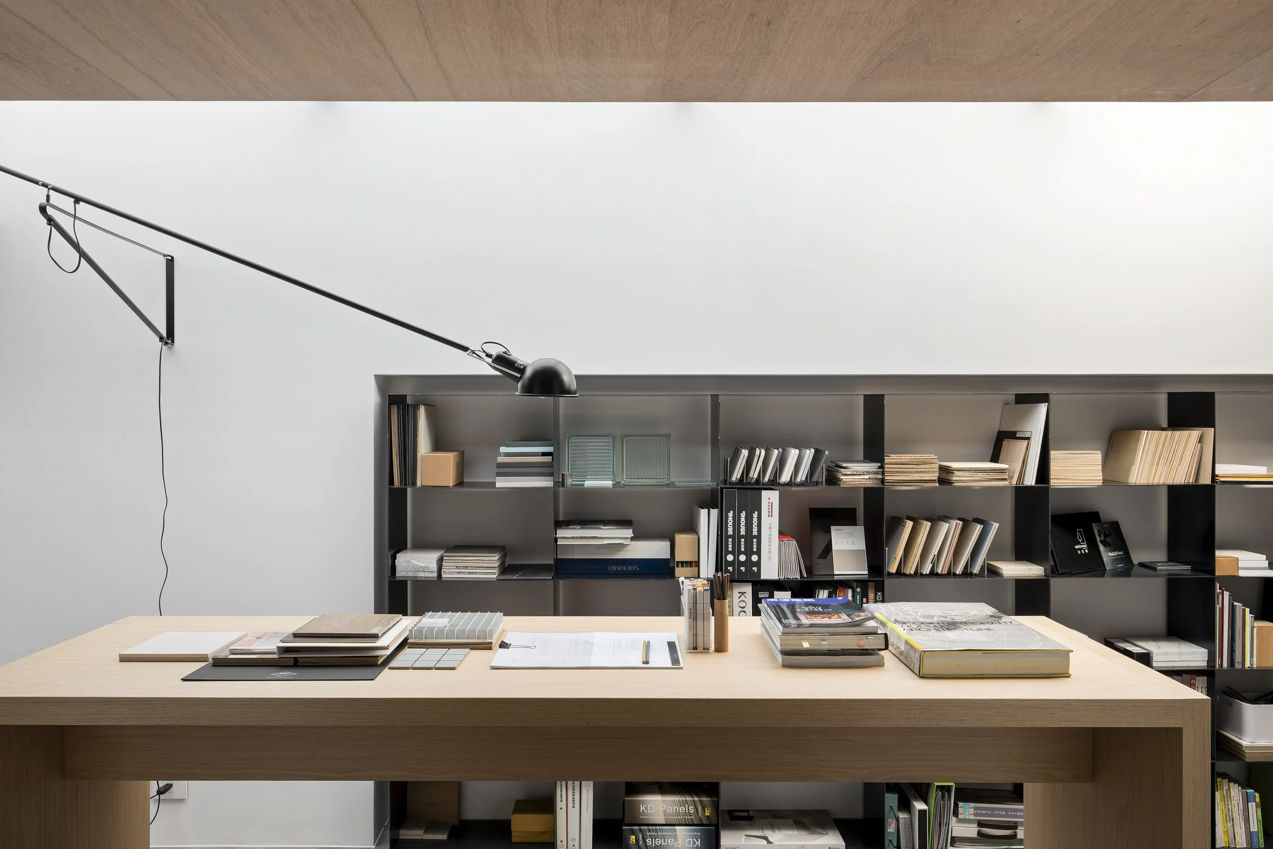 Studio In2 台北室內設計辦公室的材料討論區與 material library，以天井自然採光、高腳工作桌與建材樣品構成設計團隊的工作空間。Studio In2 interior design office in Taipei.