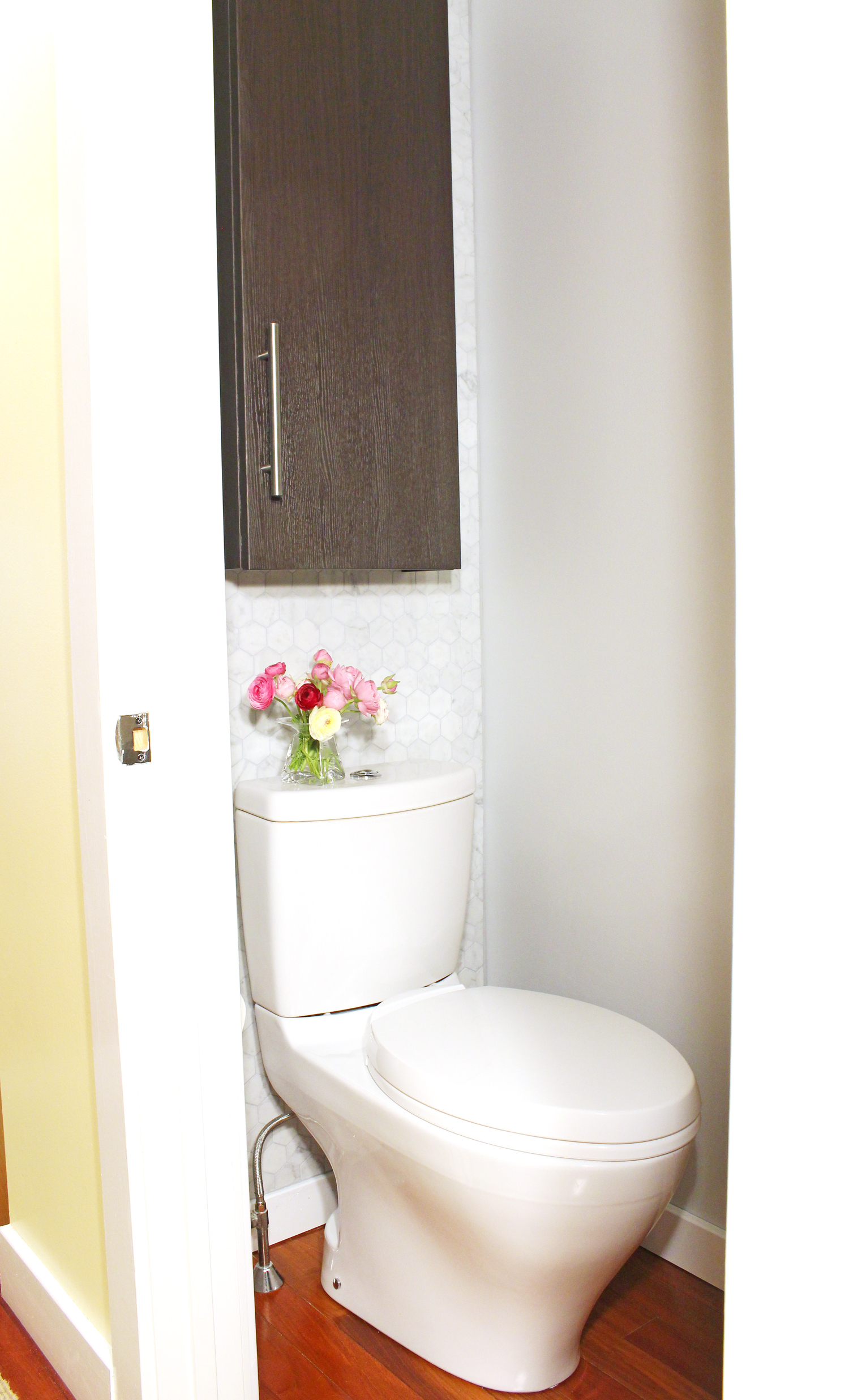 A small powder room makeover with marble hex tile and modern toilet.
