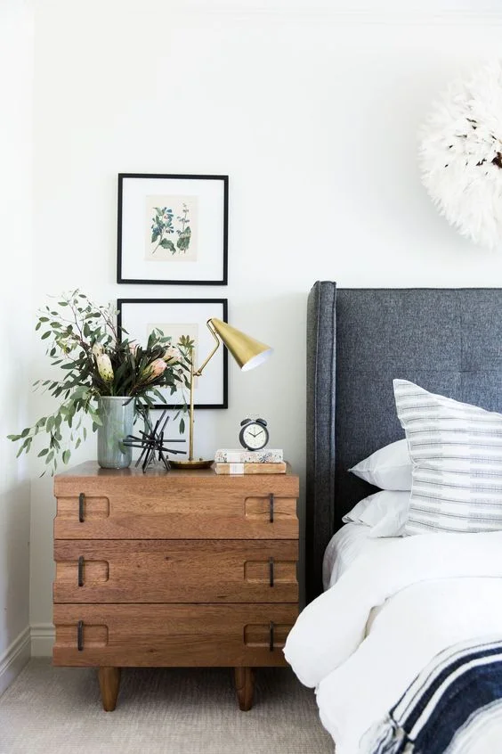 How to decorate around a bed. Option: hang stacked art above a nightstand (Design: Studio McGee). // coastal modern bedroom, gray headboard, three drawer chest nightstand 