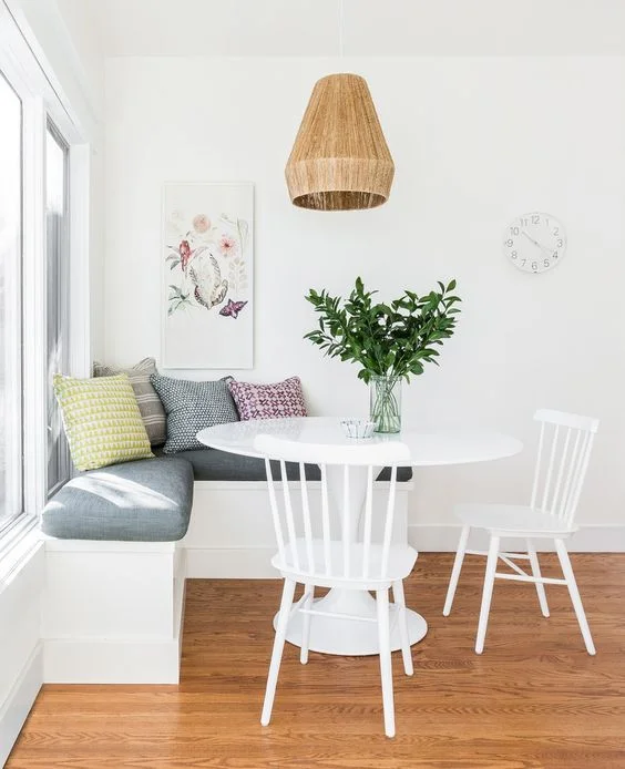 Small breakfast nook feels open and airy with white walls and furniture. Get more small space decorating tips at the Mix & Match Blog!