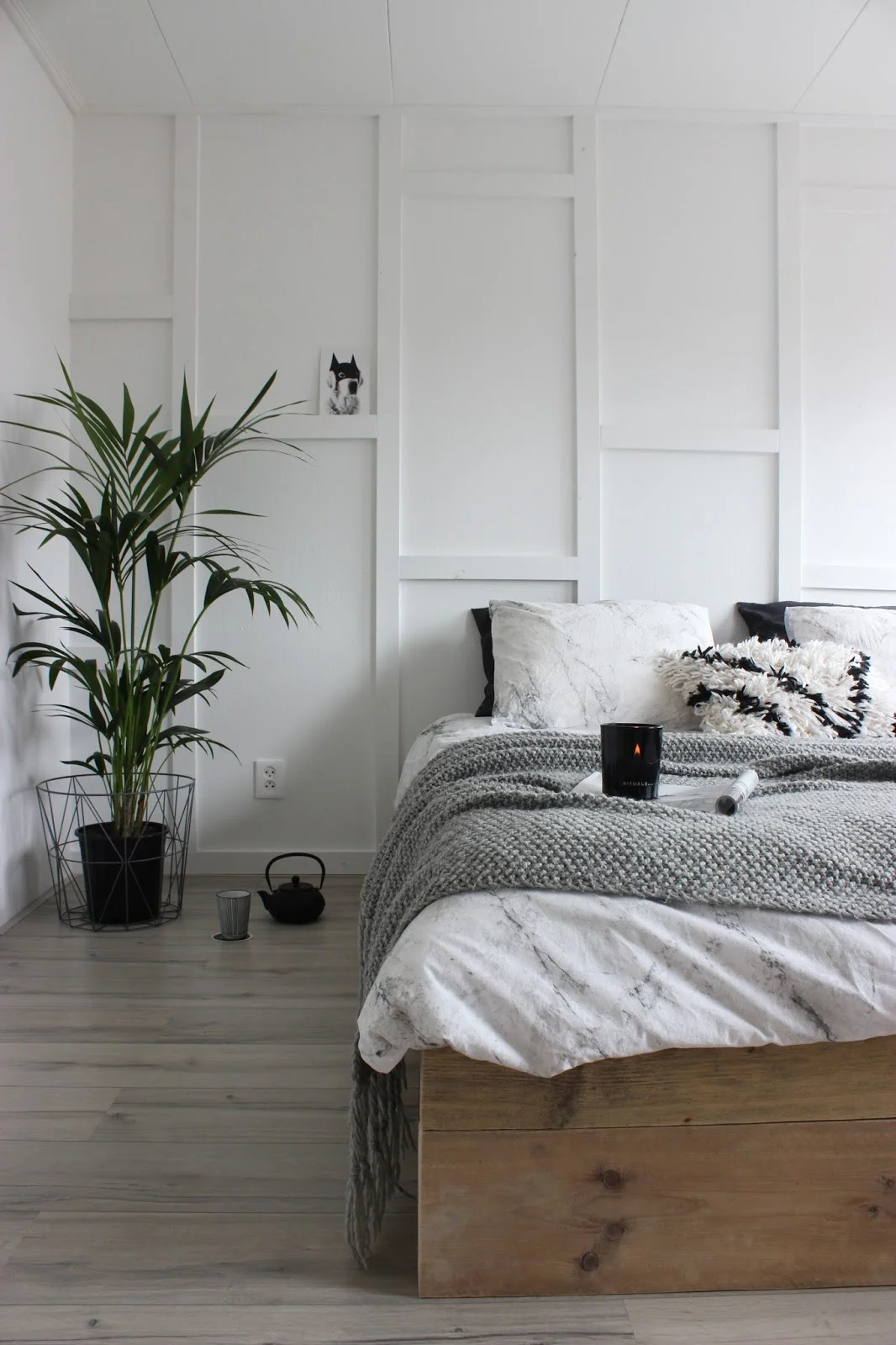 This simple, minimalist bedroom has a modern Scandinavian look with its neutral colors, cozy textures, and wall trim details.