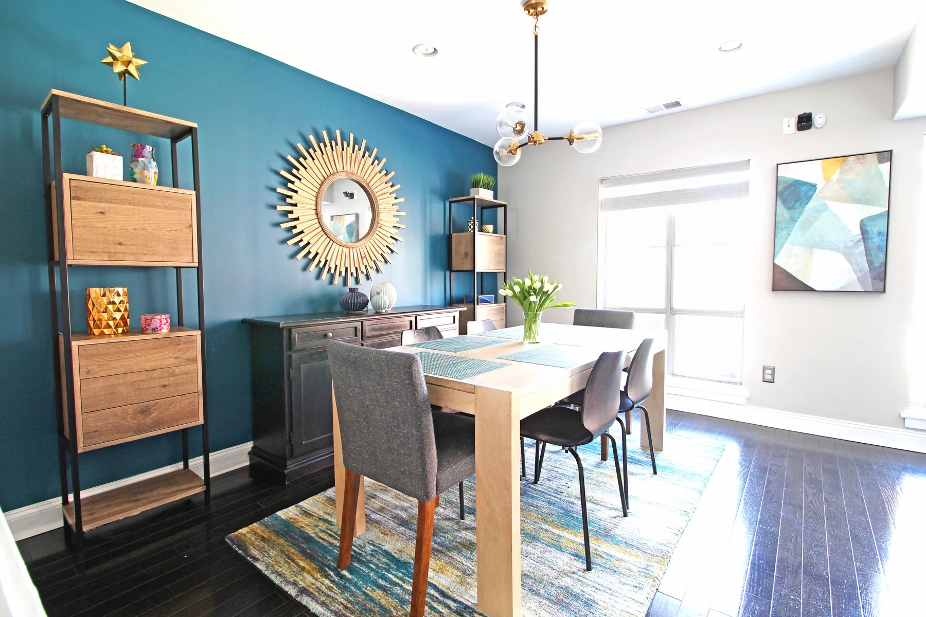 A cozy modern dining room in the heart of Philadelphia. The teal accent wall paired with light wood accents makes for a stunning and functional space for a family of four. Design and photography by Mix & Match Design Company.