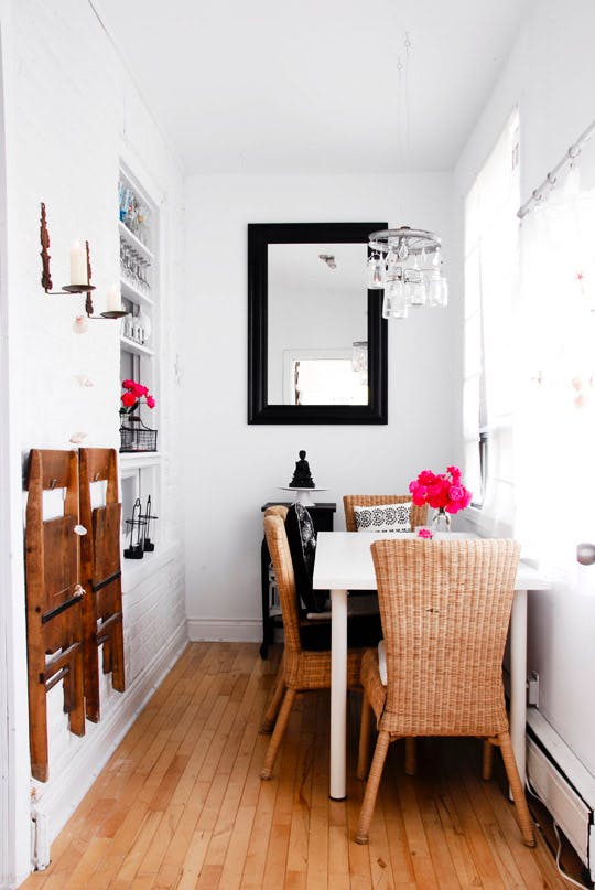 Carve out a dining area in a small home by placing a table against a wall and hanging extra dining chairs on the wall to save space. Come see more clever dining area ideas for apartments and small houses on the blog!
