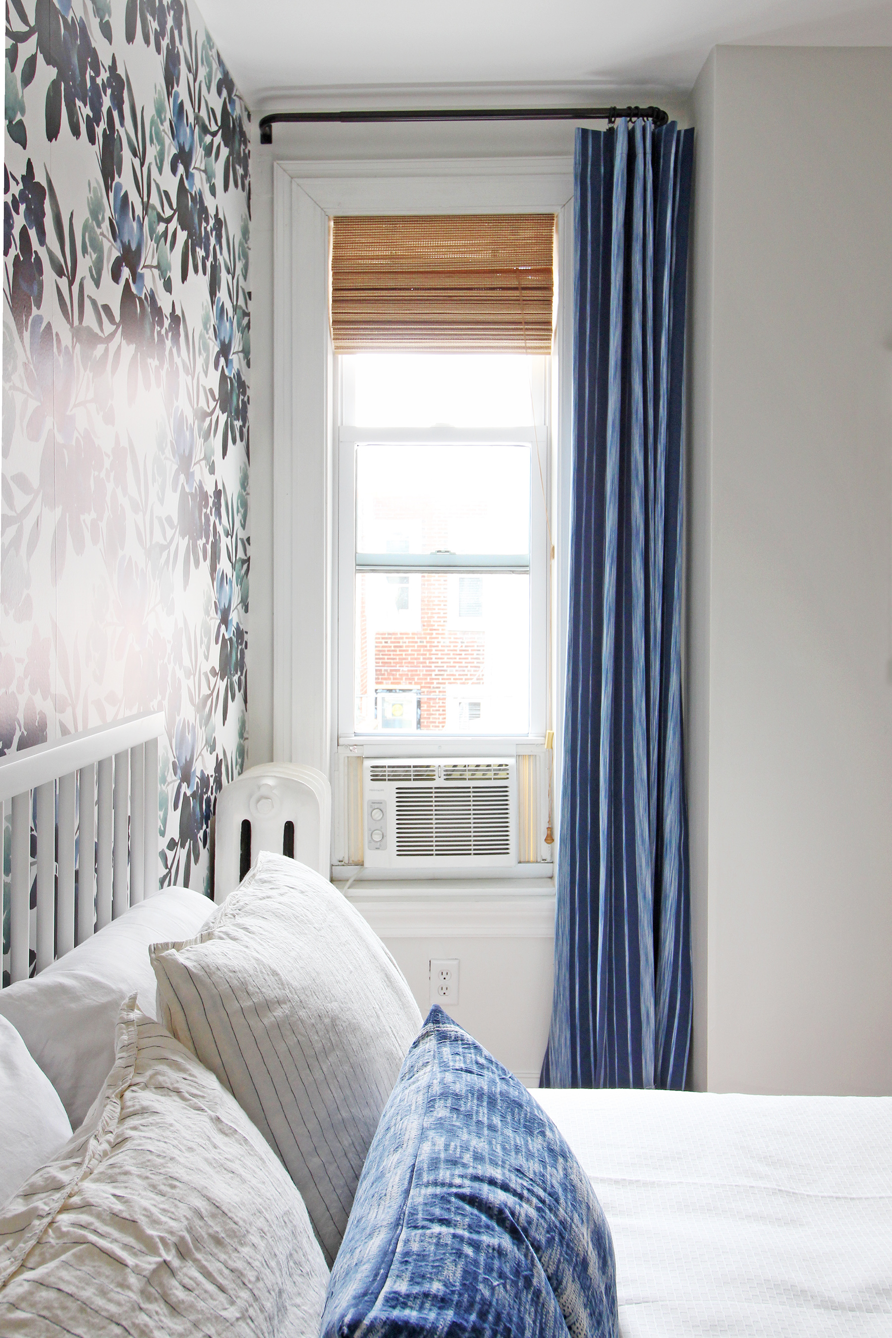 Layered window treatments add beauty and function to a small window in this blue, green, and white guest room!