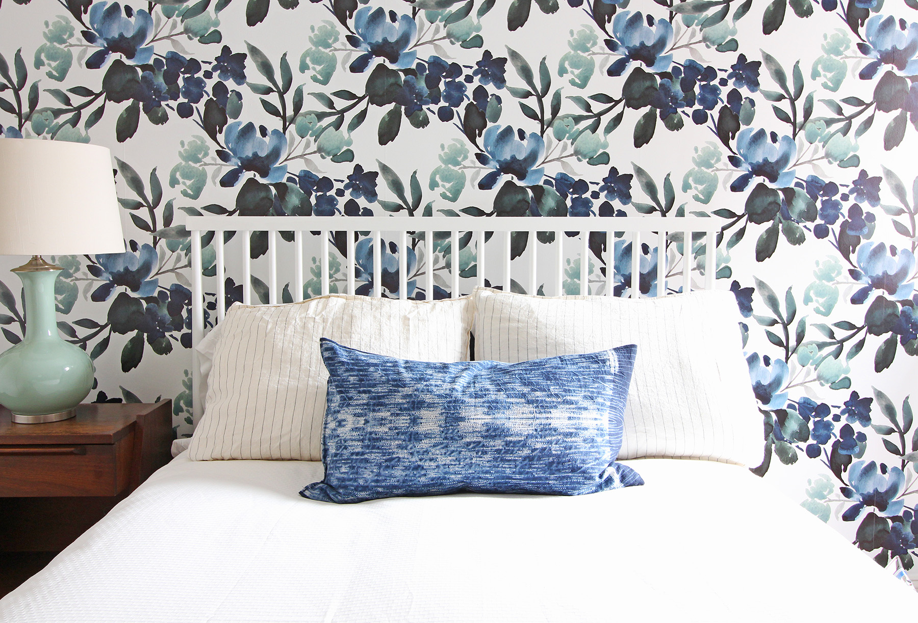 An indigo lumbar pillow is a great accent to this bold blue and green floral wallpaper in a modern farmhouse eclectic guest bedroom.