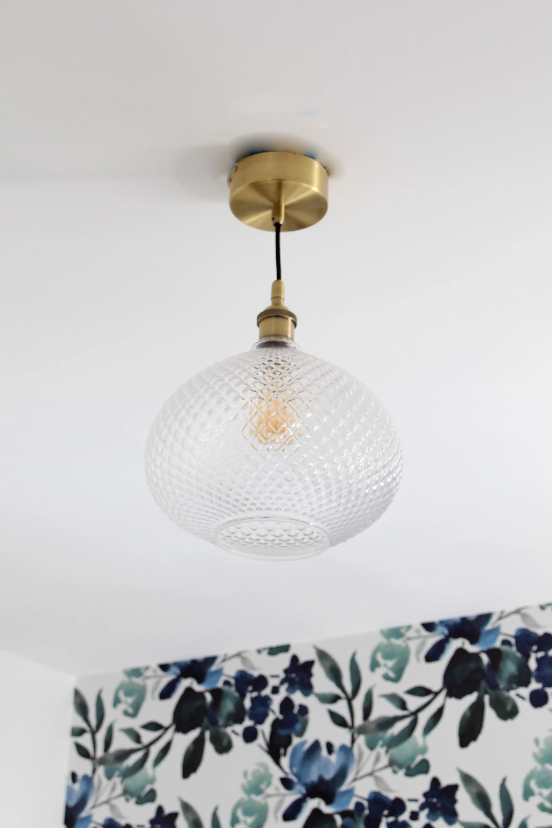 Catch a glimpse of the progress in this One Room Challenge Guest Bedroom. This week, a new cut glass pendant light from Lamps Plus went up! It's the perfect subtle, but unique touch to complement the blue and green floral wallpaper.