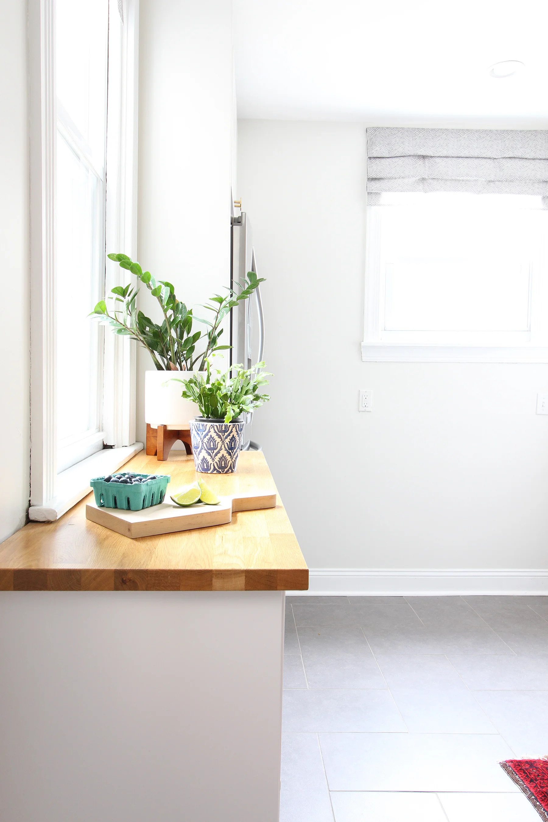 Read my review of our modern white kitchen renovation using IKEA cabinets, Caesarstone countertops, and gray tile floors two years after we renovated. The butcher block counterotps are on the "floating cabinets" we installed on the far wall of the kitchen.