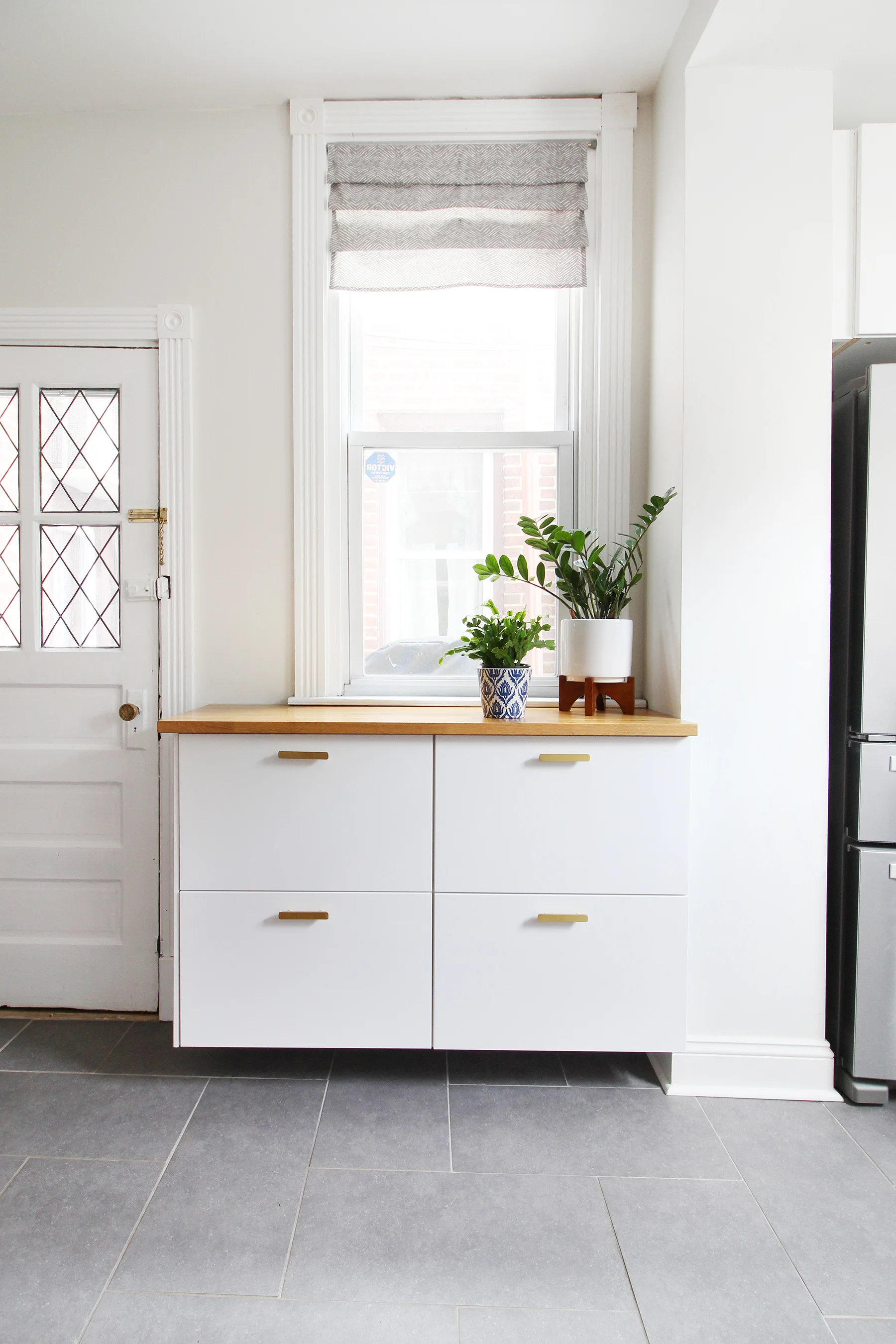 Read my review of our modern white kitchen renovation using IKEA cabinets, Caesarstone countertops, and gray tile floors two years after we renovated. We installed butcher block on this floating cabinet run and it's still going strong!
