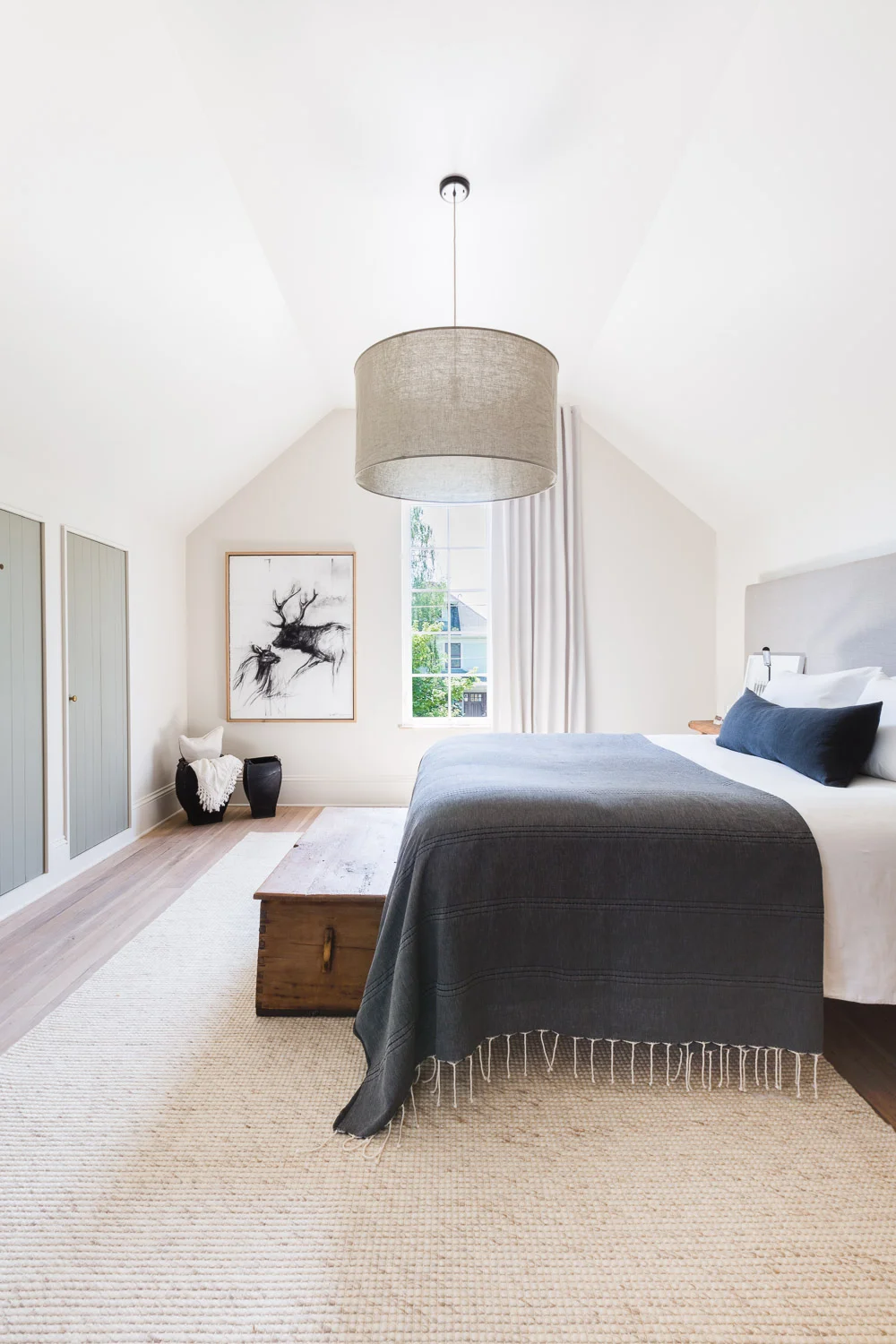 This rustic modern bedroom with vaulted ceilings and a bench at the end of the bed is cozy and inviting. For more ideas on how to use benches in your home, head to this blog post!