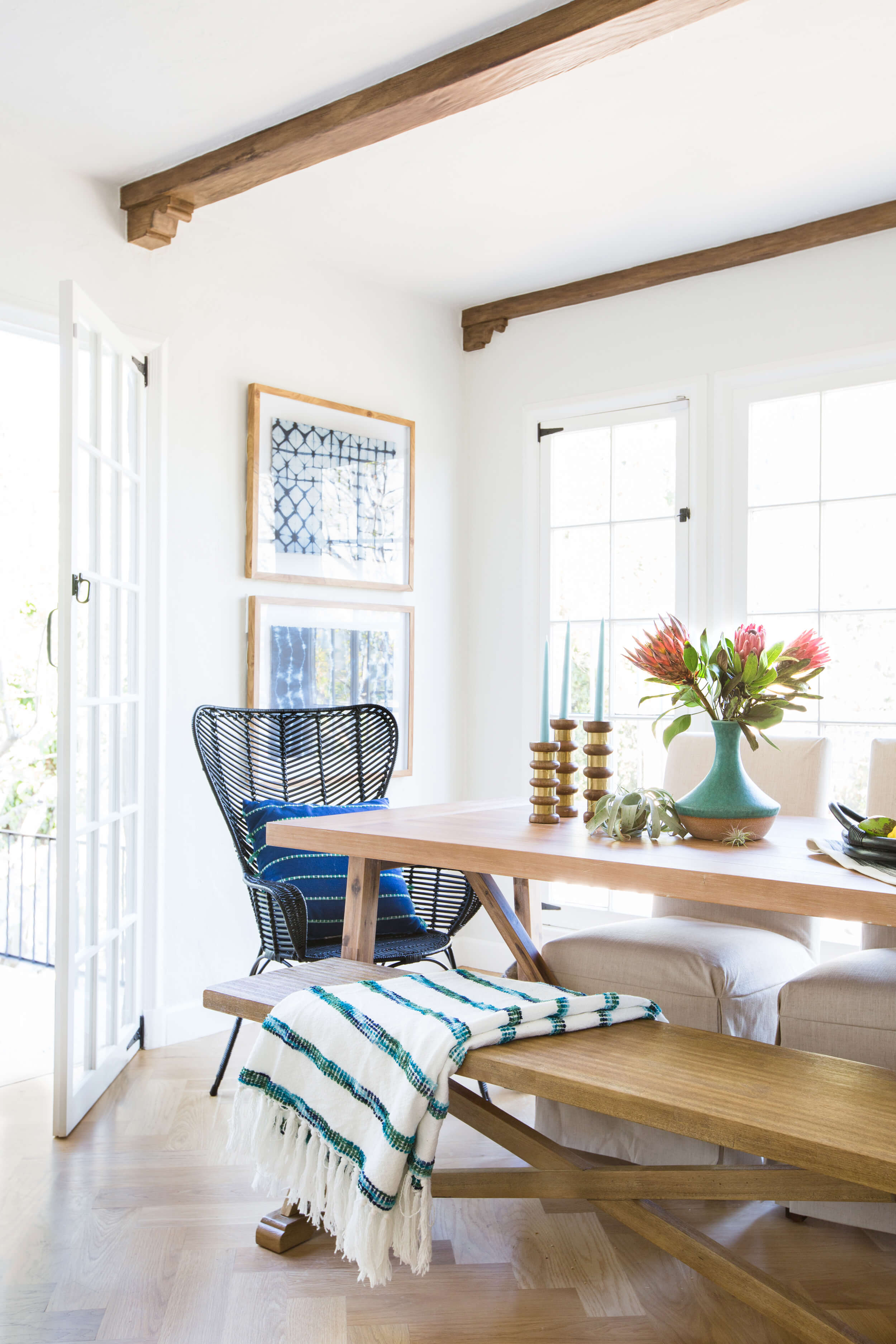 Inspiration for a coastal modern dining room. This blue and white color palette with natural wood feels warm and inviting. I love the dining bench paired with the black rattan chairs. Find out how you can get a similar look in your own home on the blog!