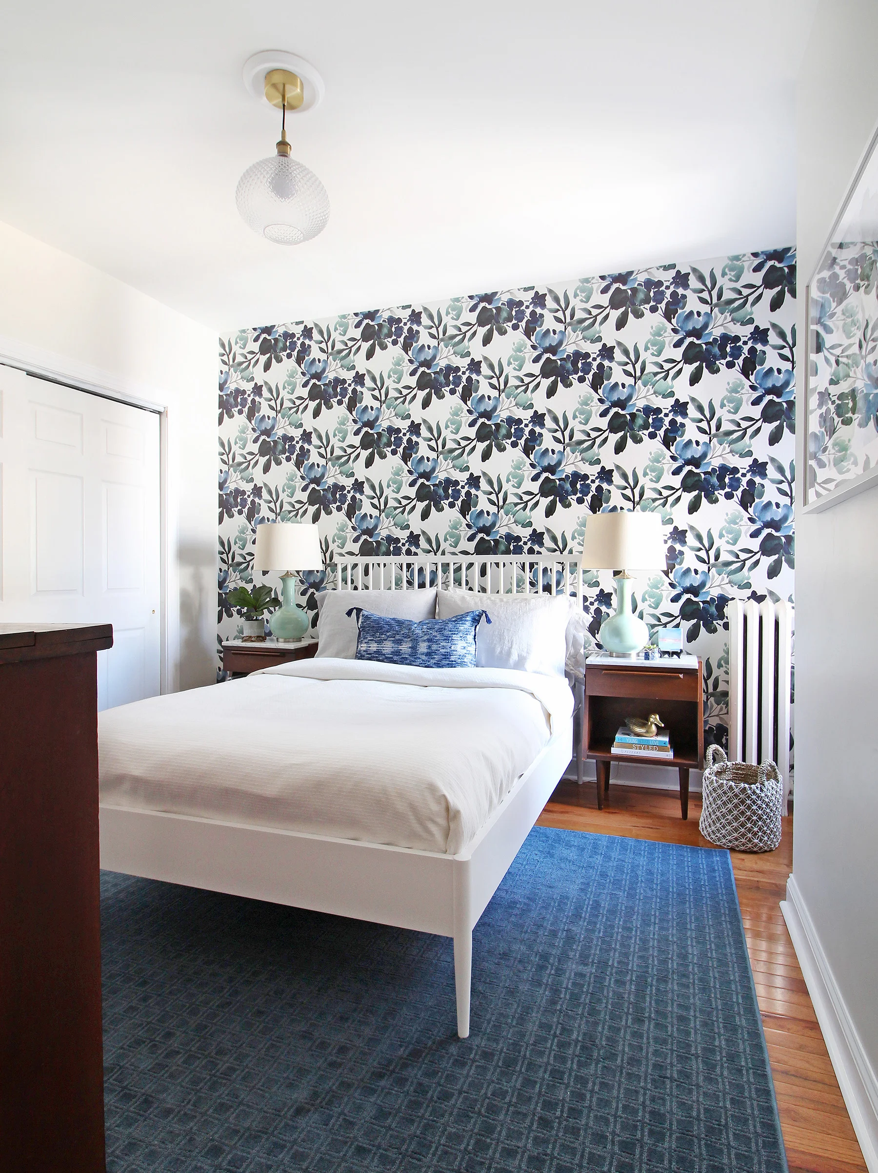 Learn how to position your furniture correctly on a rug in this blog post! Specifically, we're talking about rugs in bedrooms. This blue, green, and white modern farmhouse bedroom shows a great example of selecting the right size and placement.
