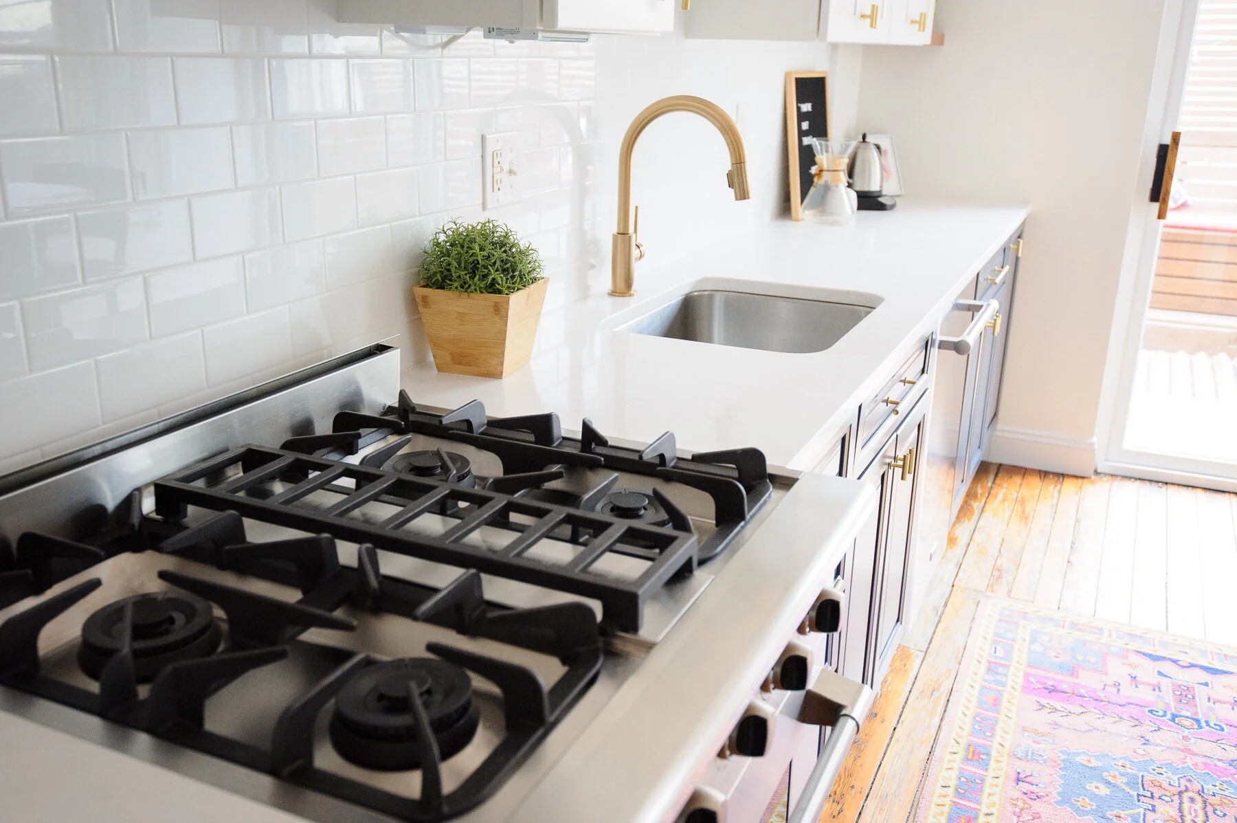 The after: a white, navy, and brass kitchen makeover in a Philadelphia row home. This kitchen got a serious refresh to give it a modern, clean, and cozy look. We chose Hale Navy for the lower cabinets, white subway tile, marble-like quartz countertops, and matte brass cabinet hardware. Designed by Mix & Match Design Company. Photos by Nate Photographic.
