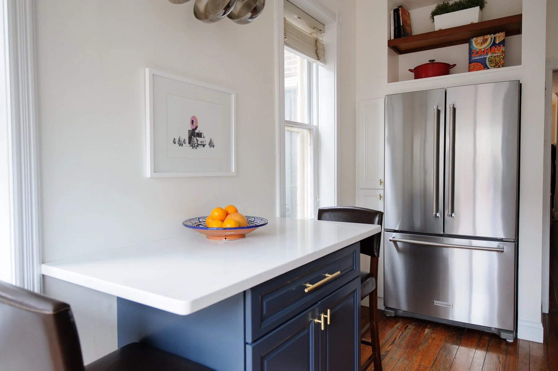 The after: a white, navy, and brass kitchen makeover in a Philadelphia row home. This kitchen got a serious refresh to give it a modern, clean, and cozy look. We chose Hale Navy for the lower cabinets, white subway tile, marble-like quartz countertops, and matte brass cabinet hardware. Designed by Mix & Match Design Company. Photos by Nate Photographic.