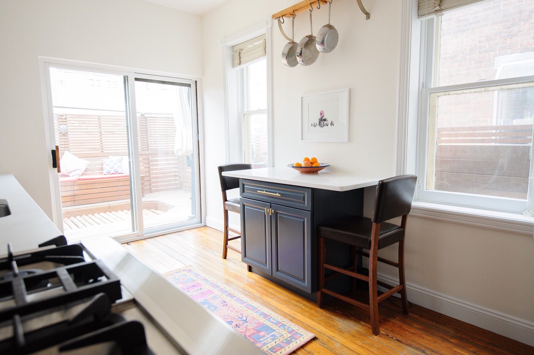 The after: a white, navy, and brass kitchen makeover in a Philadelphia row home. This kitchen got a serious refresh to give it a modern, clean, and cozy look. We chose Hale Navy for the lower cabinets, white subway tile, marble-like quartz countertops, and matte brass cabinet hardware. Designed by Mix & Match Design Company. Photos by Nate Photographic.