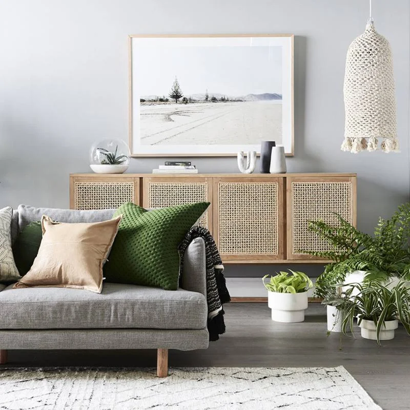 Gorgeous woven door sideboard (cane) in a modern living room. Love the gray sofa with moroccan style rug and the oversized landscape art above the sideboard.