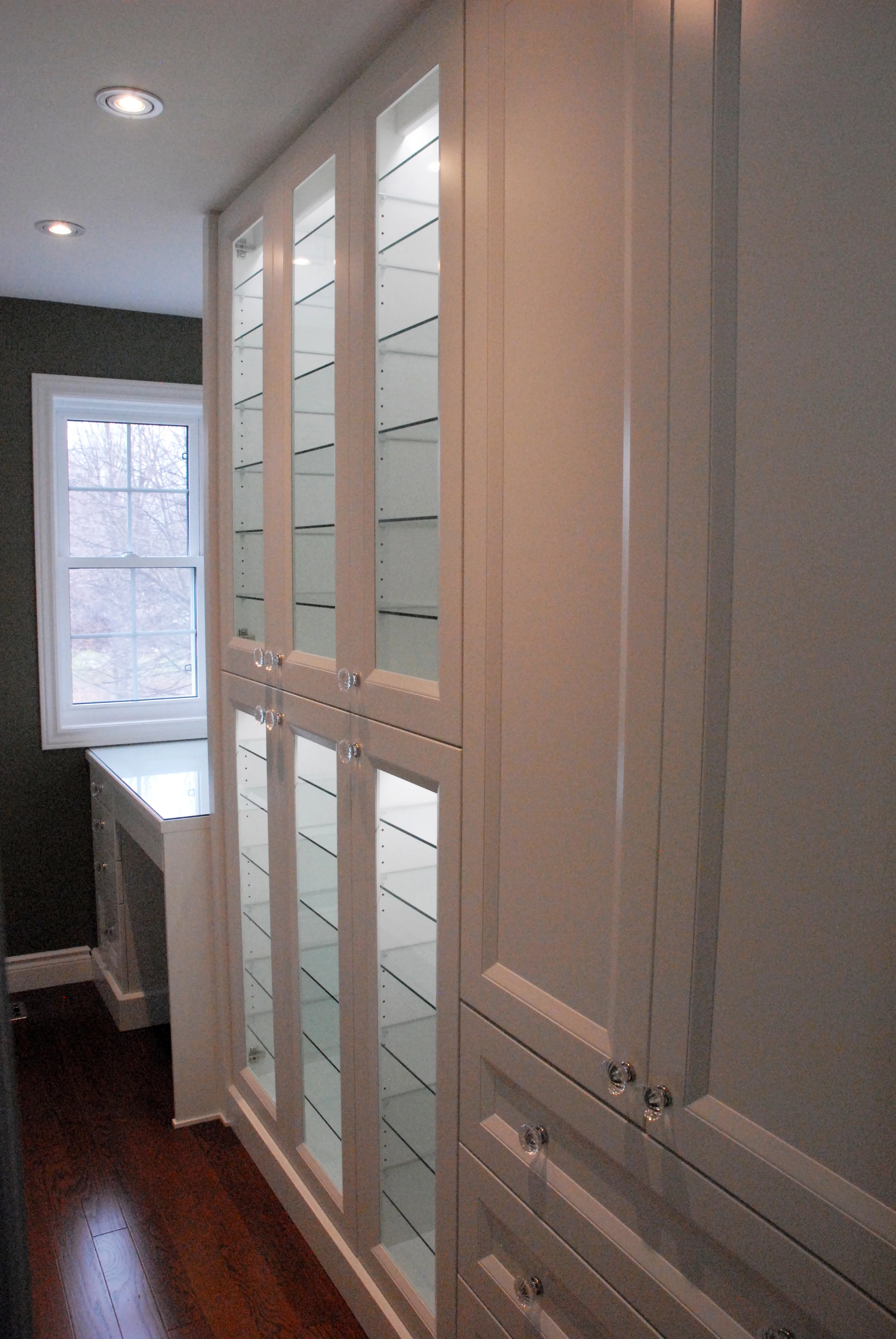 Closed cabinet side, with wide drawers, shelves inside cabinets, glass door display/ storage and makeup desk
