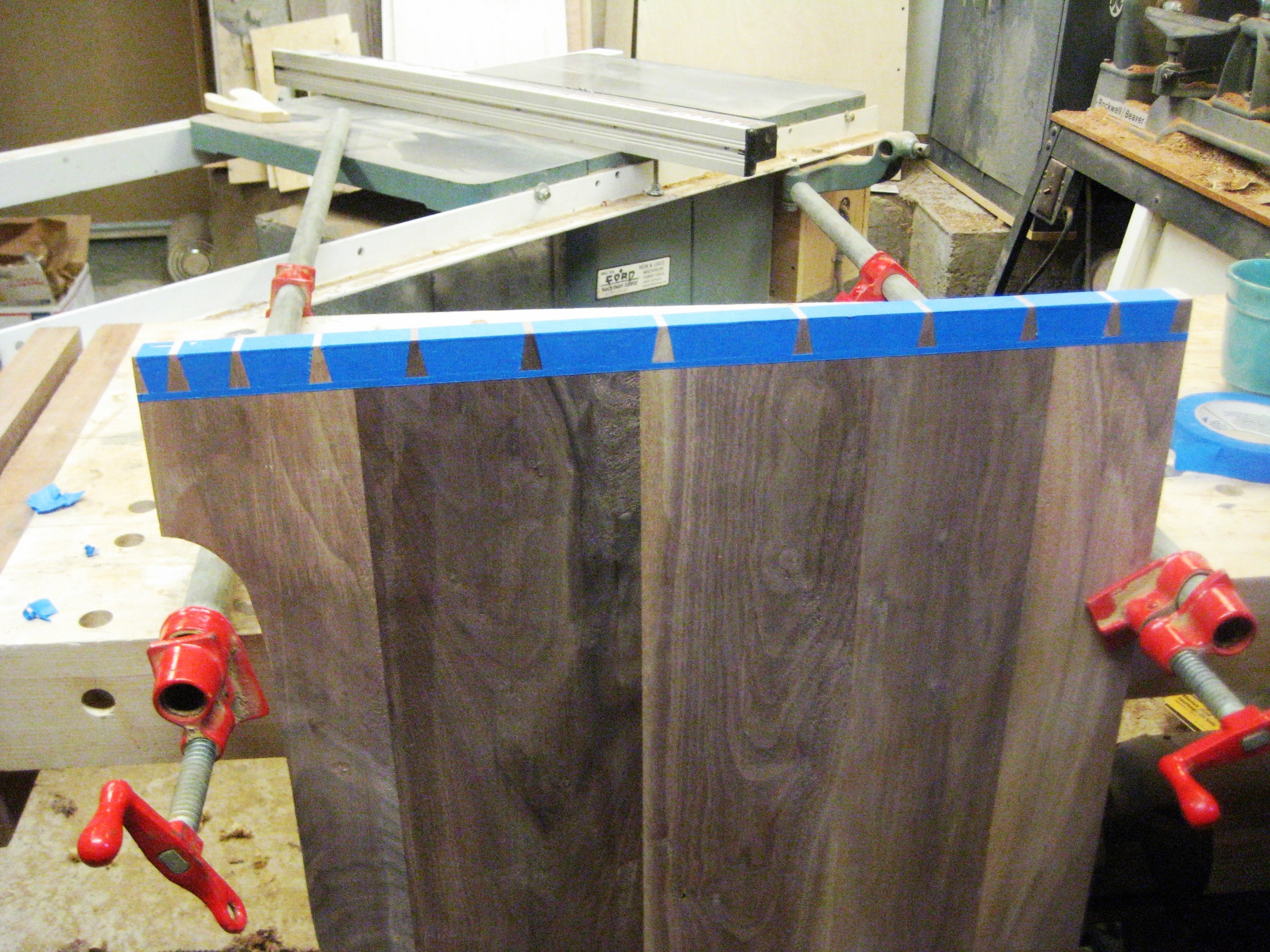 Here the dovetails are laid out on the panel. I use blue tape because there are so many tails, and the tape helps highlight the exact lines that i will need to cut. 