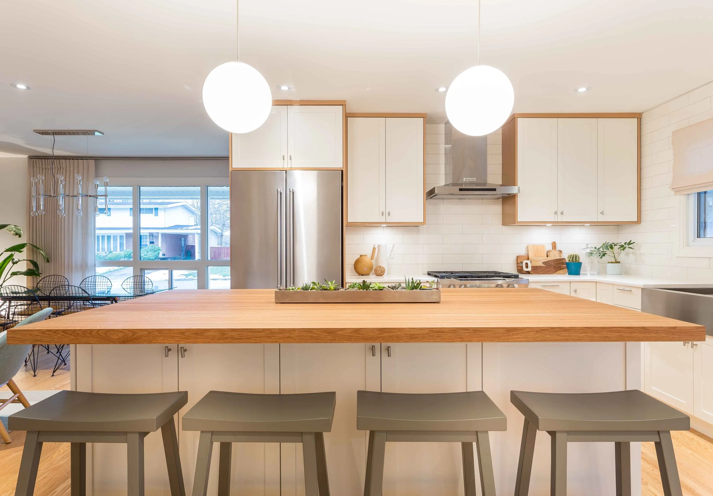 Simple globe style pendant lights and modern stools chosen by KMSalter Design bring home the mid century vibes