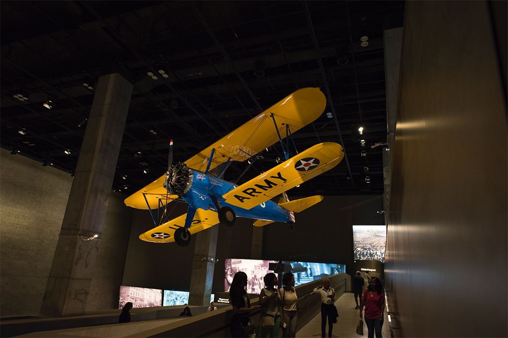 TUSKEGEE AIRPLANE. Overhead is the PT-13D Stearman Kaydet training aircraft used by the Tuskegee Airmen. Photo credit: Luka Kito