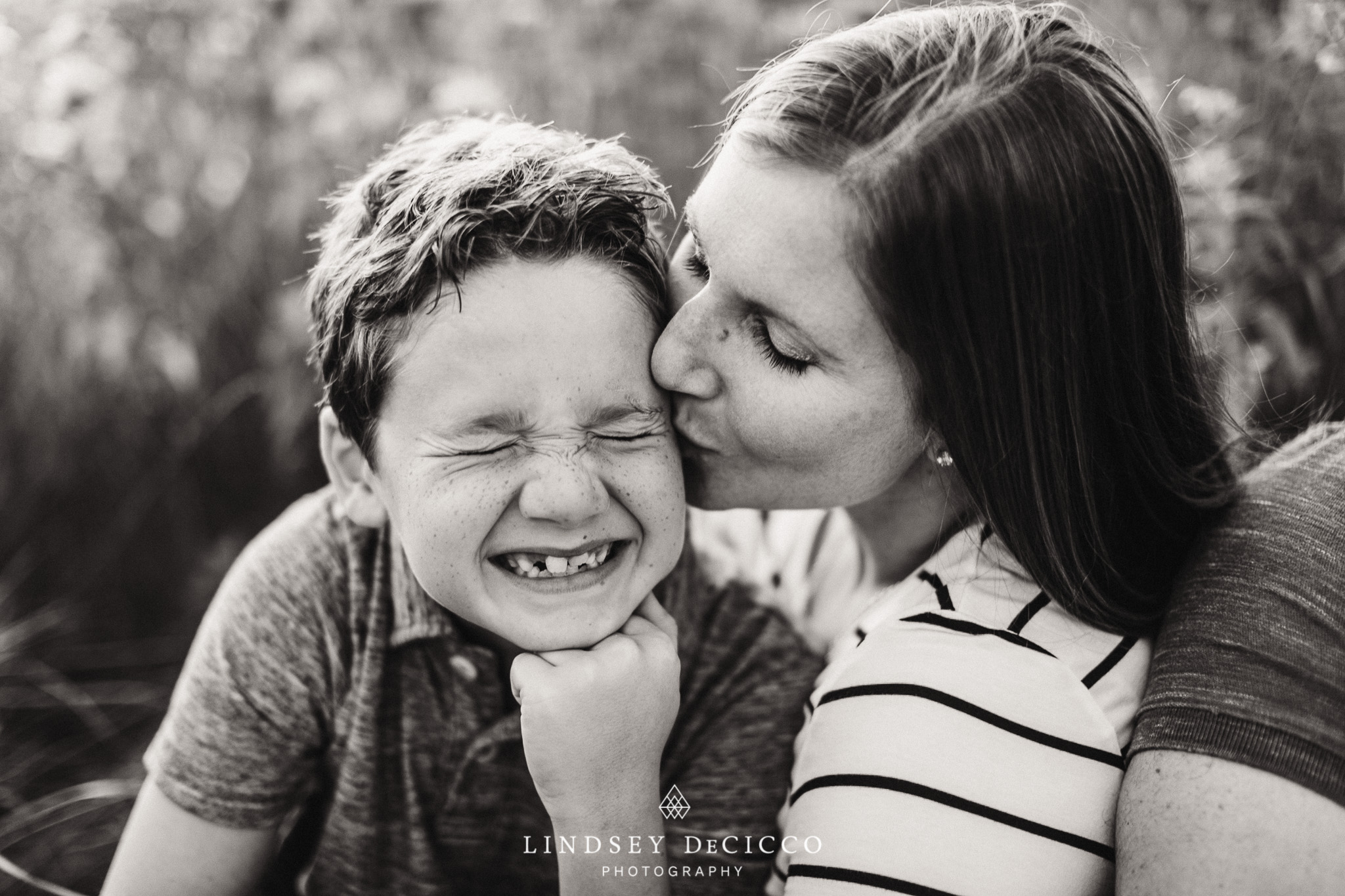 mom and son with freckles not enjoying kiss, black and white