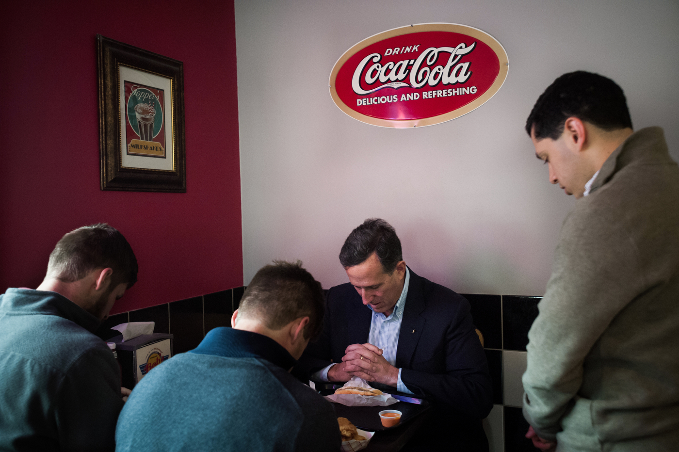  Republican U.S. presidential candidate Rick Santorum prays with members of his campaign staff during lunch between stops in Le Mars, Iowa on October 30, 2015. 