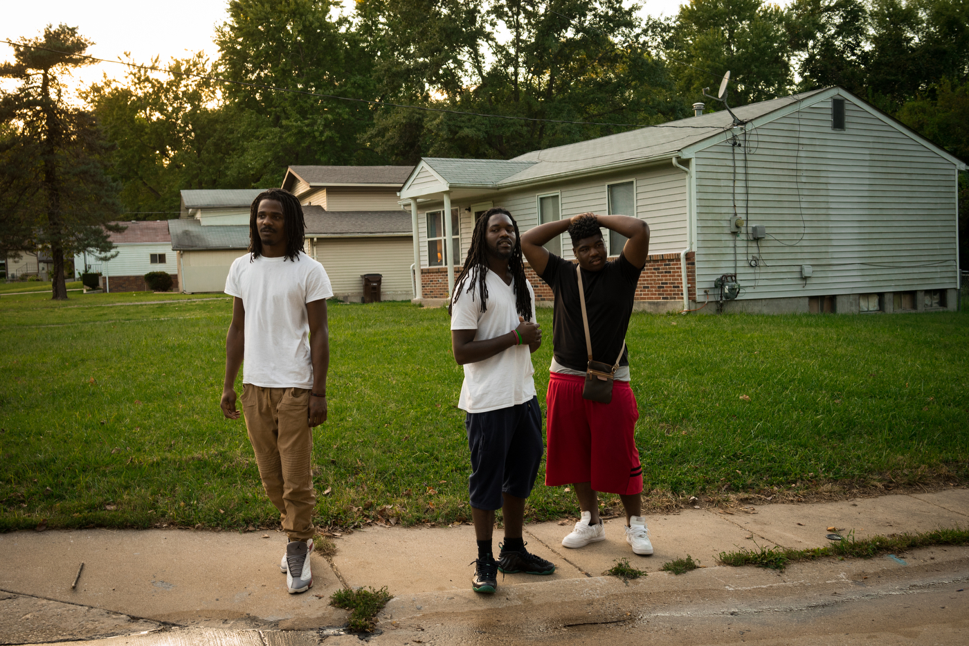 Ant, Jorden, and a friend watch as two kids (not seen) fight during a friendly basketball game in the Bermuda neighborhood of Ferguson.