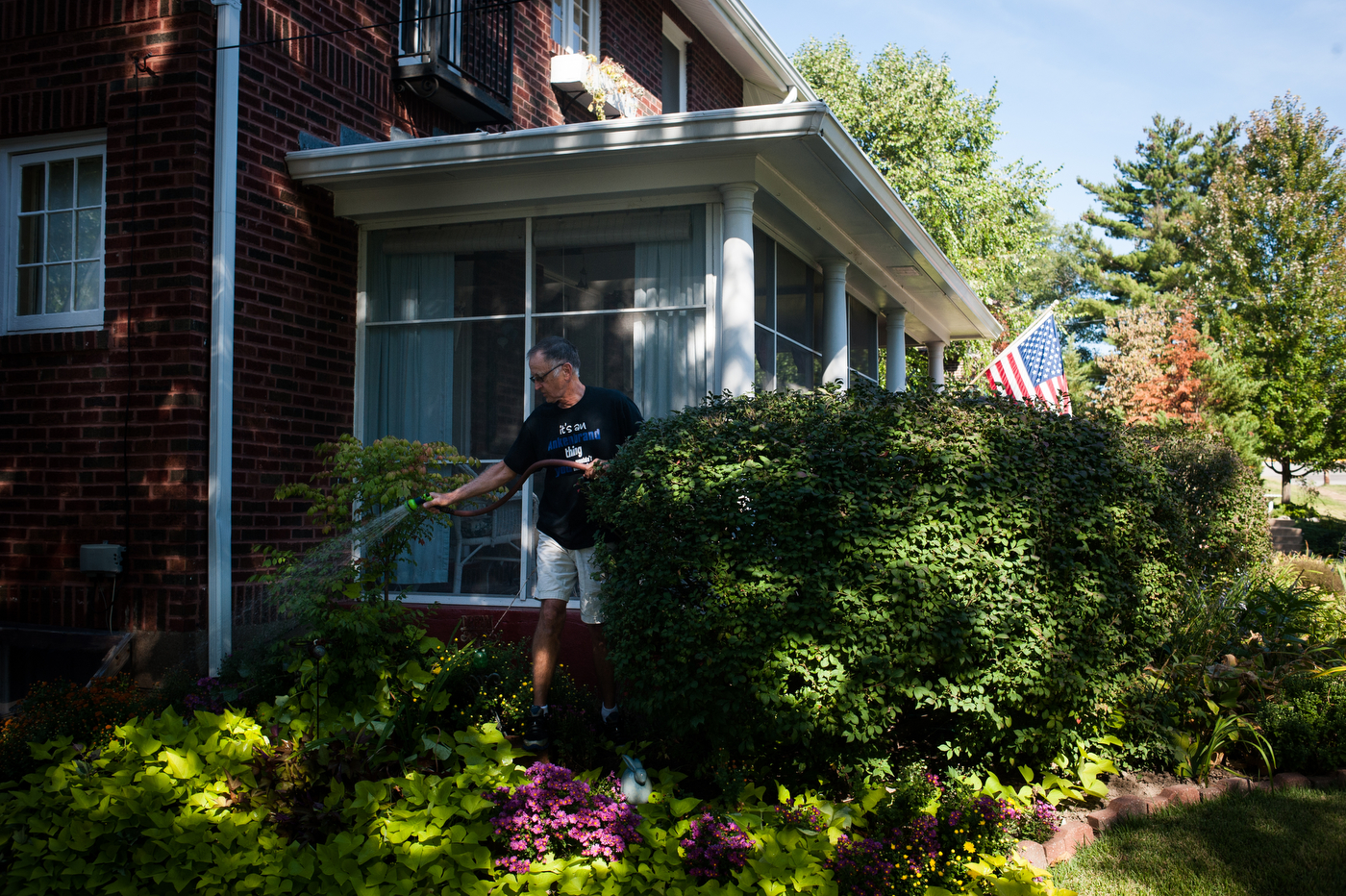 Ank Ankenbrand waters the lush gardens of his home in Historic East Ferguson, an area rarely targeted by code enforcement officers.