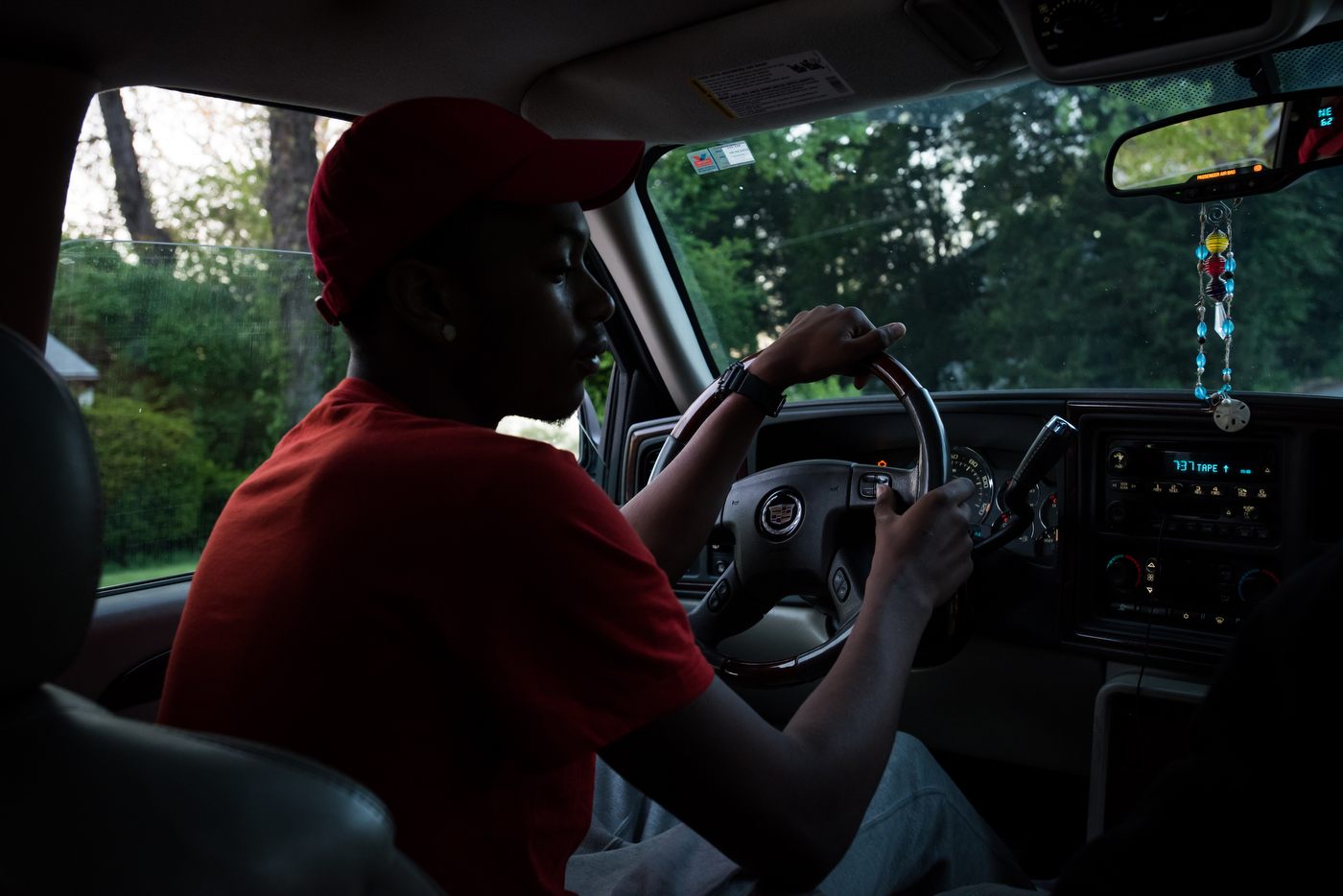Redd waits for a friend in his Cadillac Escalade before going to the liquor store to buy more Hennessey. Redd and his friends hang out on the street outside of a parent's home, under their watchful eye.