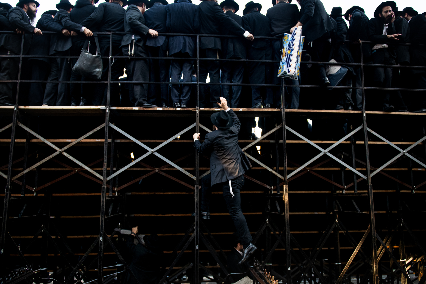  A Chabad-Lubavitch rabbi climbs the back of some stands as thousands gather for a group photo in front of the movement's headquarters in the Crown Heights neighborhood of Brooklyn, NY. 
