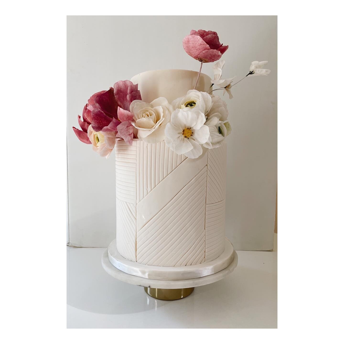 A beautiful day for Misa and Andy! Congrats!The cake is highlighted with geometric lines softened with edible flower arrangement in bold contrast between white and fuchsia. A combination of sugar and wafer paper flowers are used in this arrangement :