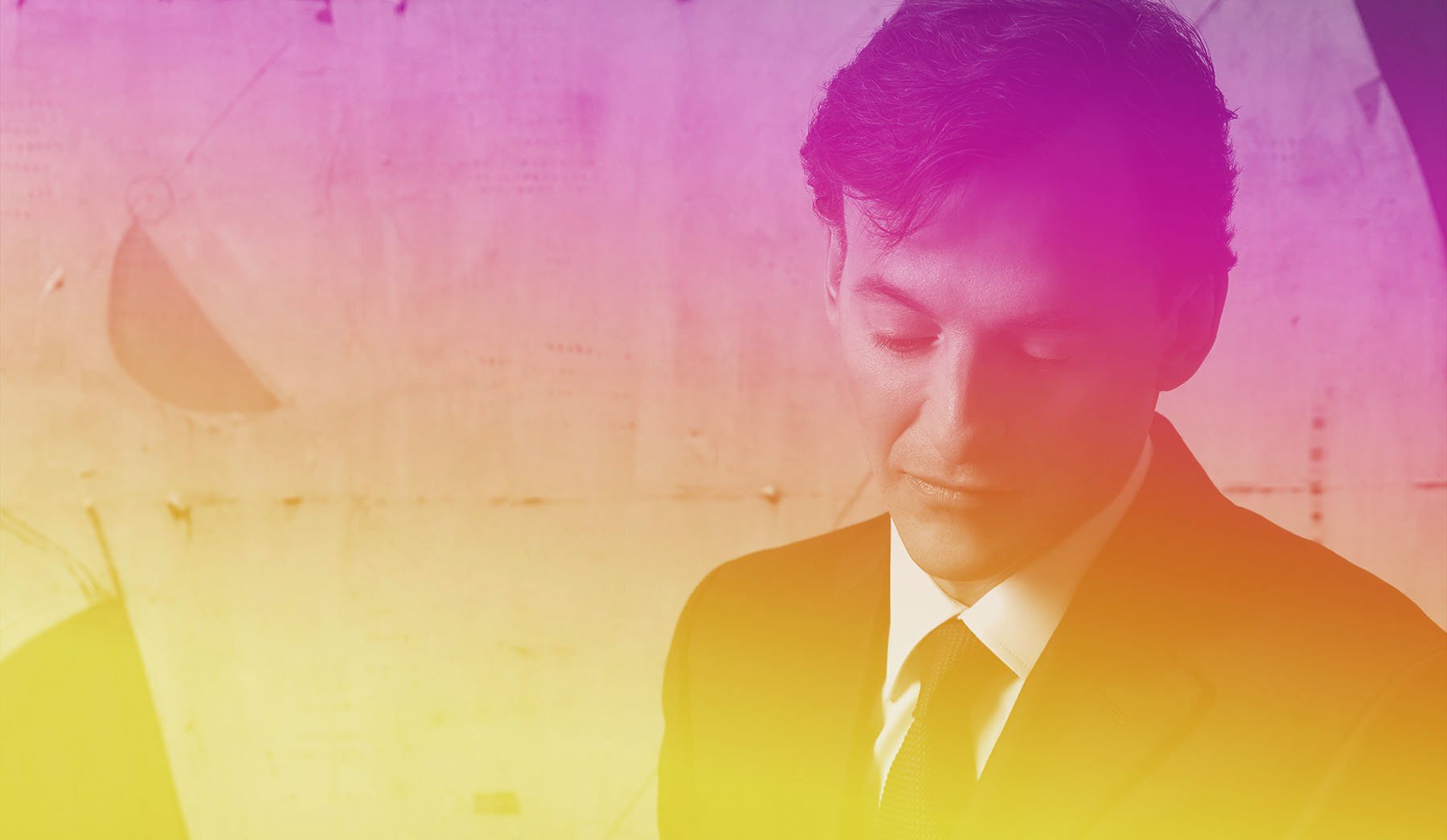 Bruce Levingston with head bowed, in pink and yellow light.jpg