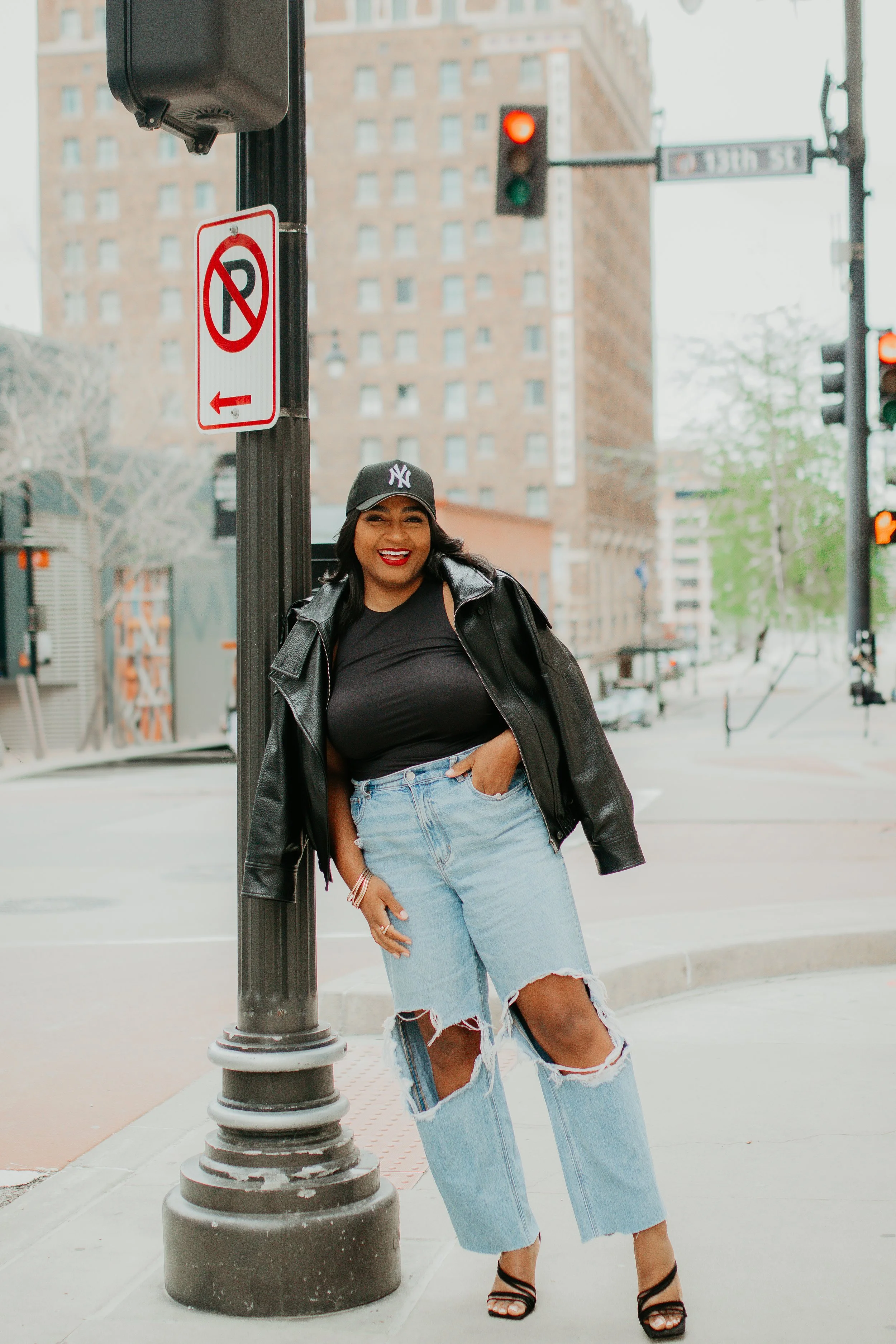 Trendy all-black outfit idea with ripped jeans, black heels, and a leather jacket for transitional weather.
