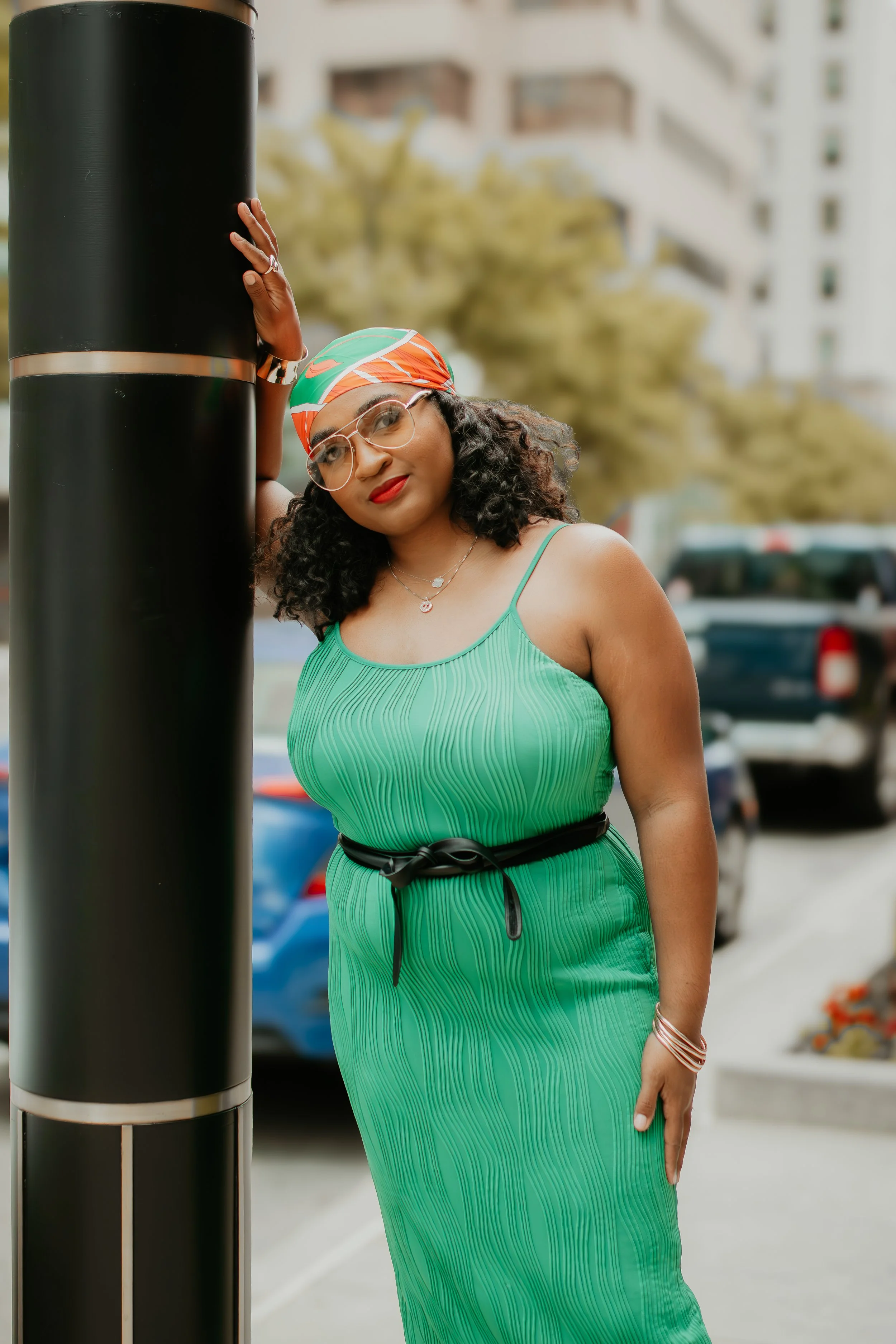 Chic summer outfit featuring a green dress styled with black heels, a skinny black leather belt, and elevated neutral accessories.