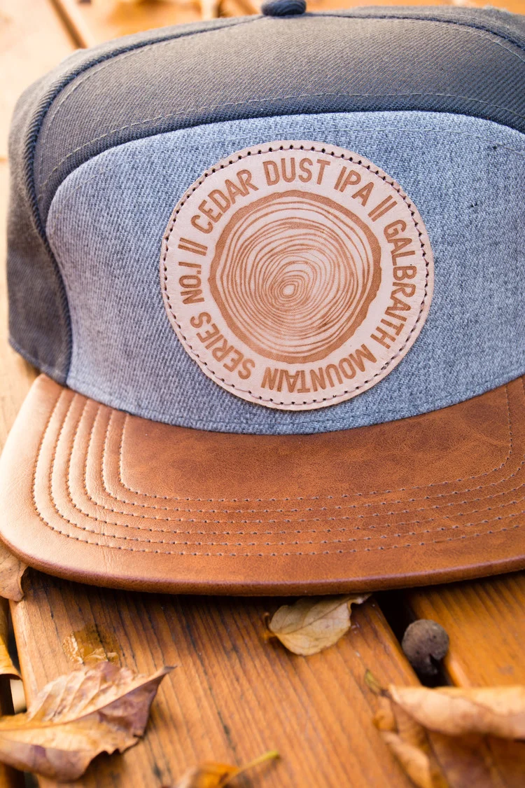 5-Panel Cedar Dust Cap Custom, one-of-a-kind five-panel Cedar Dust Hat I designed from scratch, materials and all. The cap features a distressed leather bill with two-tone gray panels. I created the cedar dust logo and worked with Blind Alley Leather Co. to create the burned patches. Each hat's patch is a little bit different making it a truly unique piece. More...