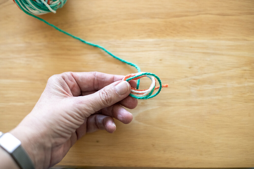  After a few loops, slip the yarn off of your fingers. Pinch it with your not-dominant hand so you can wind around those loops with the other hand. 