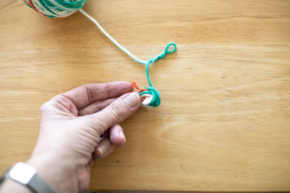  Turn the yarn and fold it in half so the ends meet together. Hold it with your not-dominant hand so you can wrap yarn going in a new direction. 