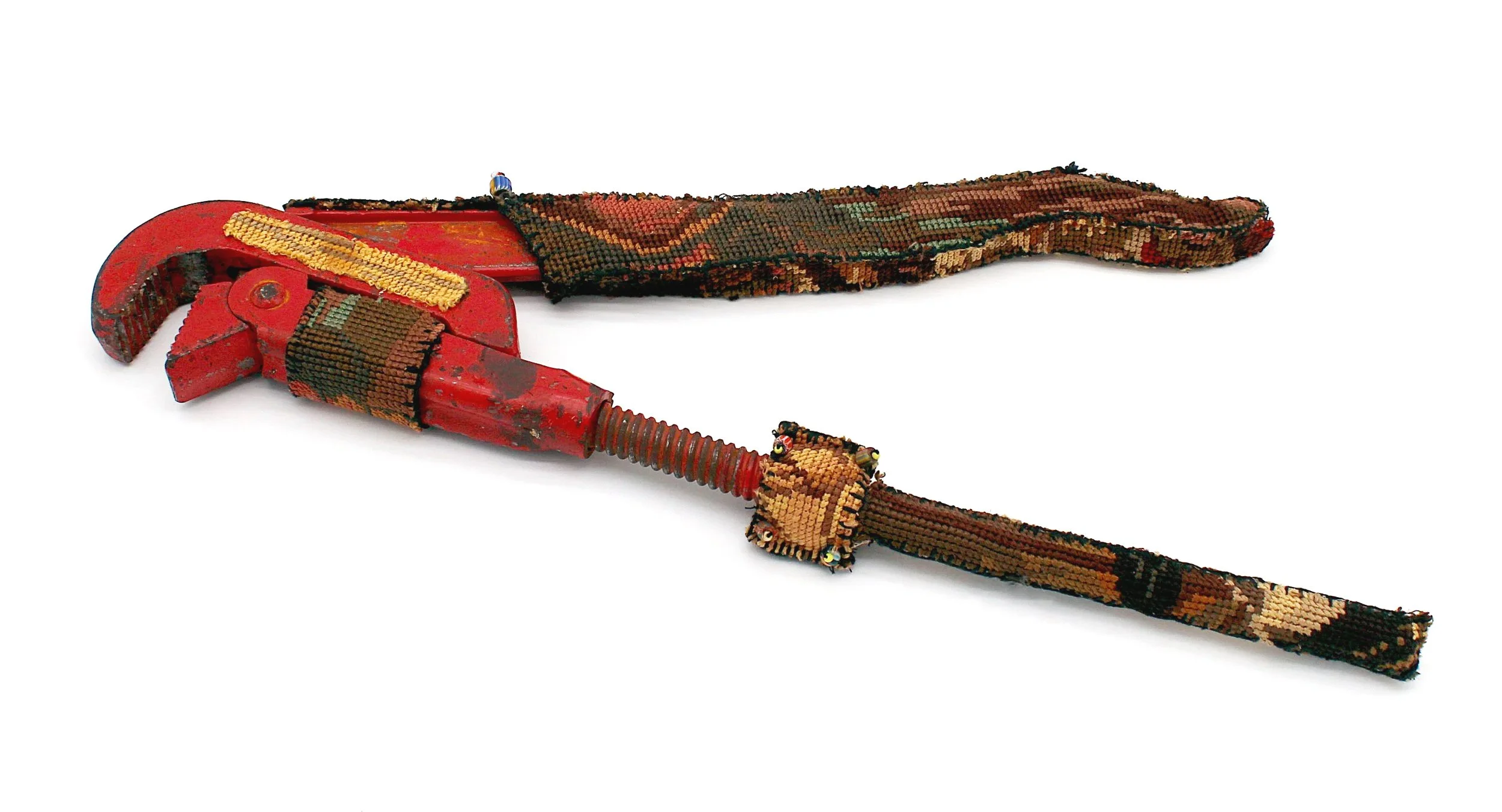 A vintage red wrench wrapped with a cross-stitch of the Rembrandt painting The Night Watch.