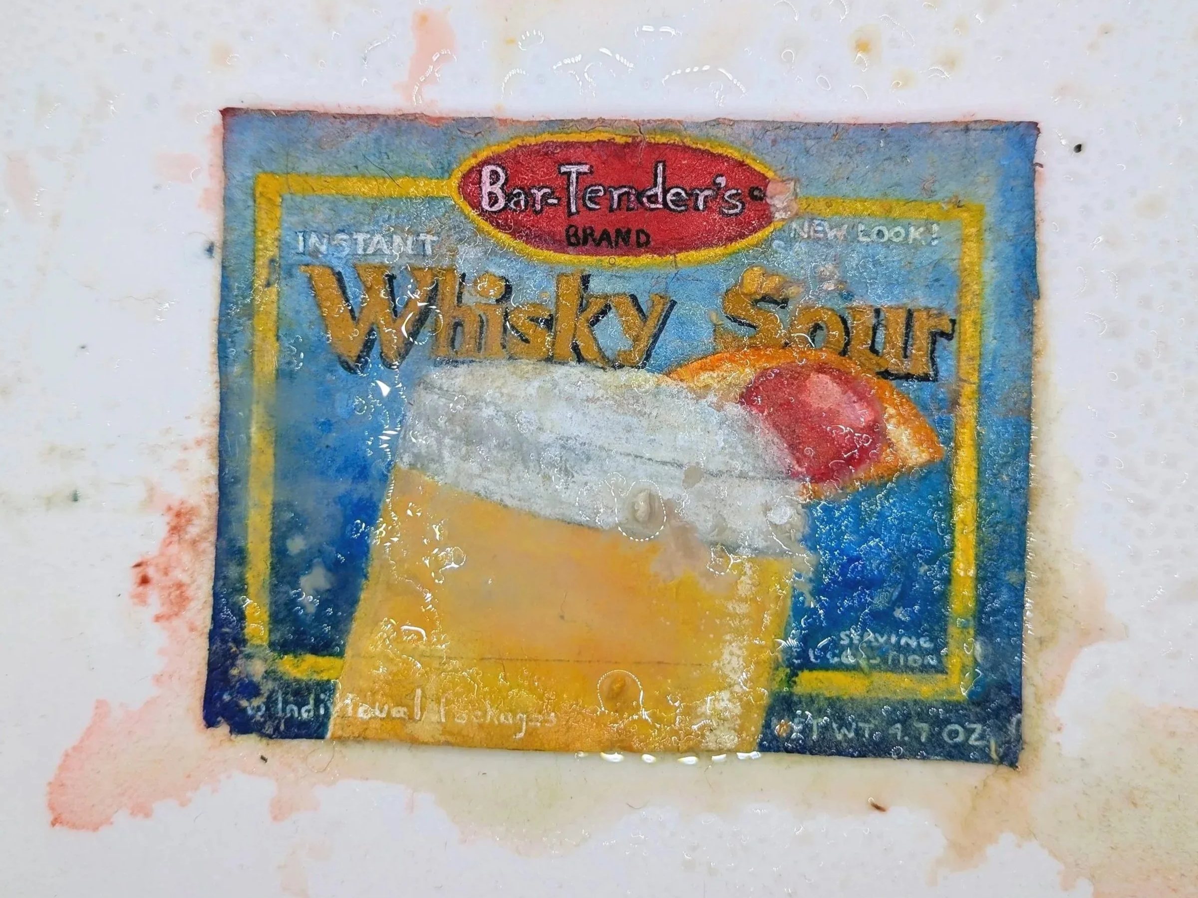 Close-up of a vintage, worn packet of Bar Tenders brand whiskey sour cocktail mix, with visible text and colorful design, covered in water droplets.