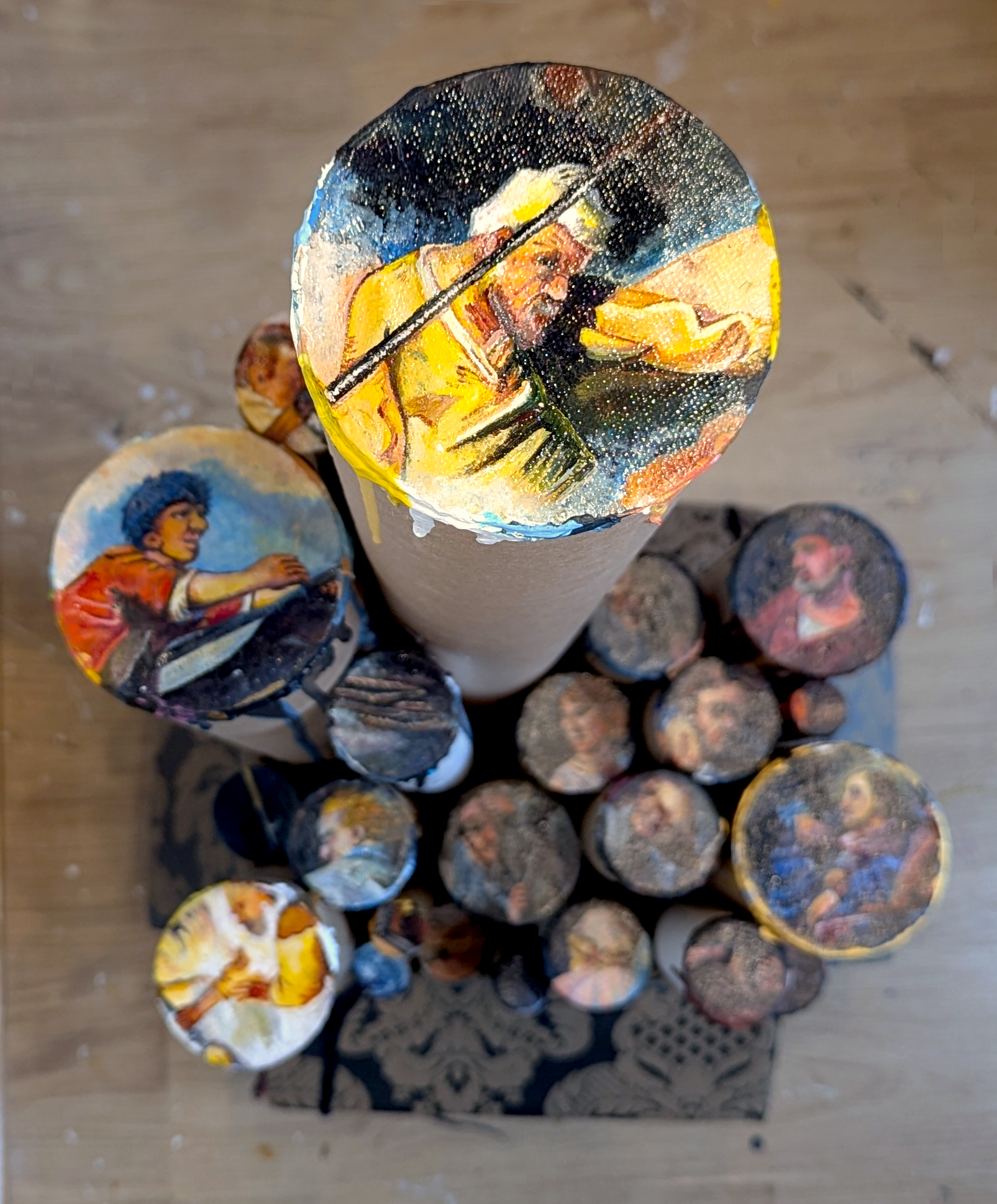 Top view of portraits painted on the ends of different lengths and diameters of poster tubes