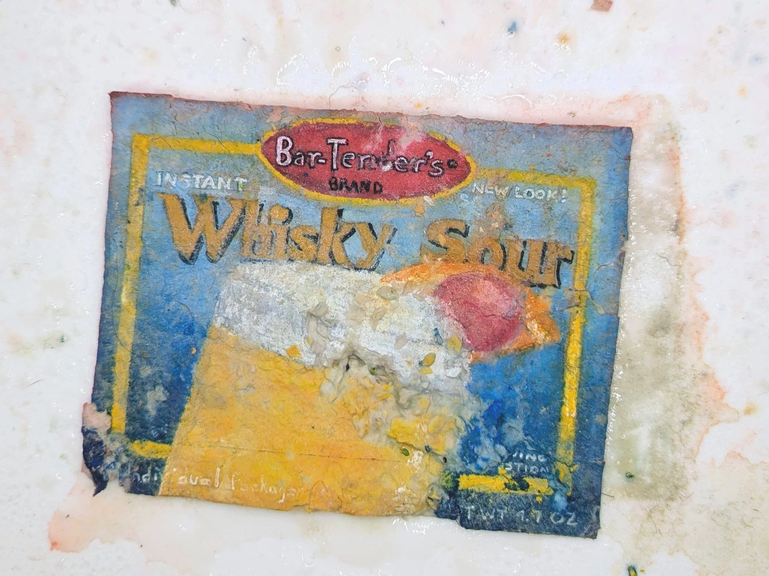 A paper seed bomb painted to look like a package of whiskey sour mix