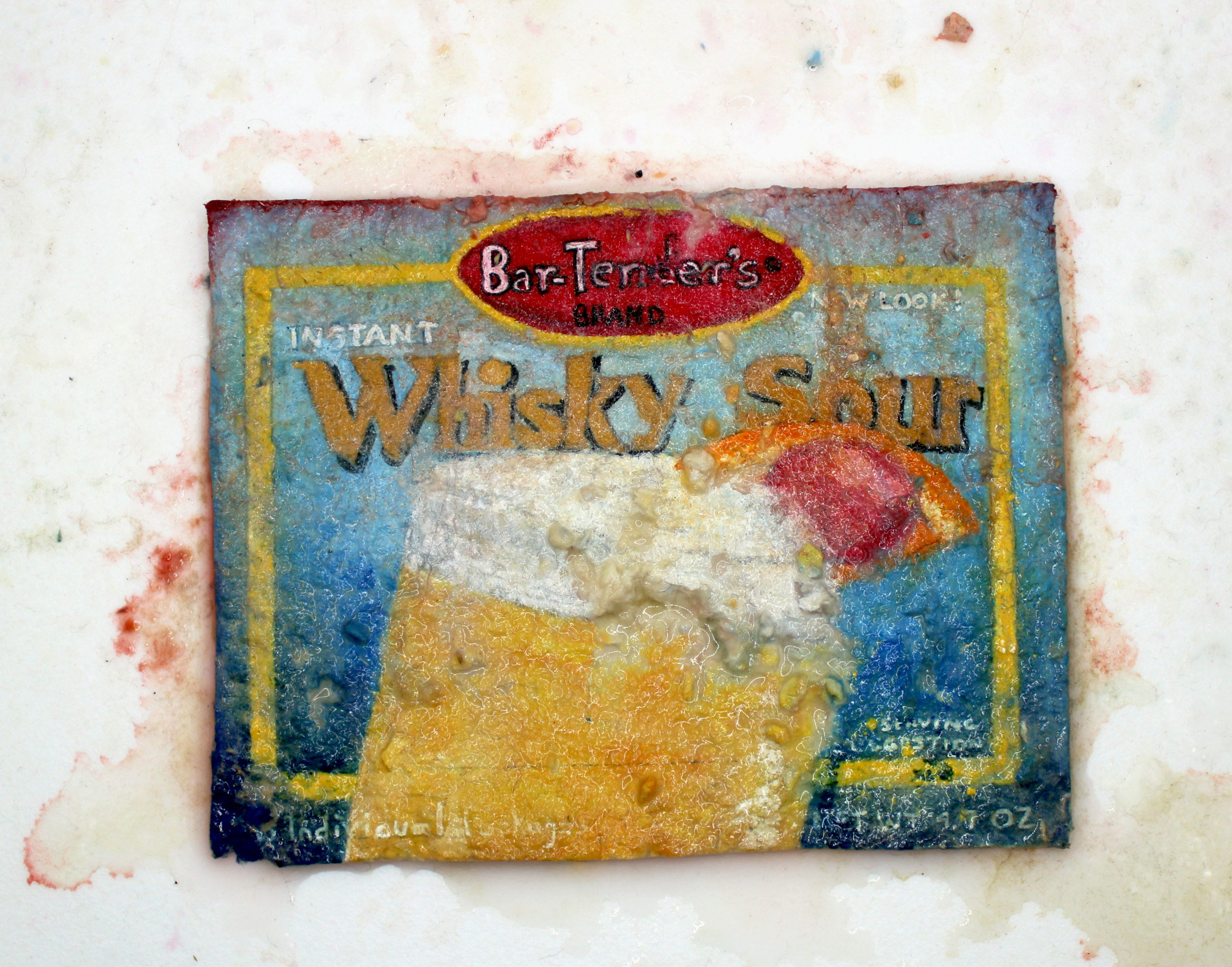 Close-up of a worn and faded label on a box of Whiskey Sour instant drink mix, showing the text "Bar-Tenders Brand" and some decorative graphics.